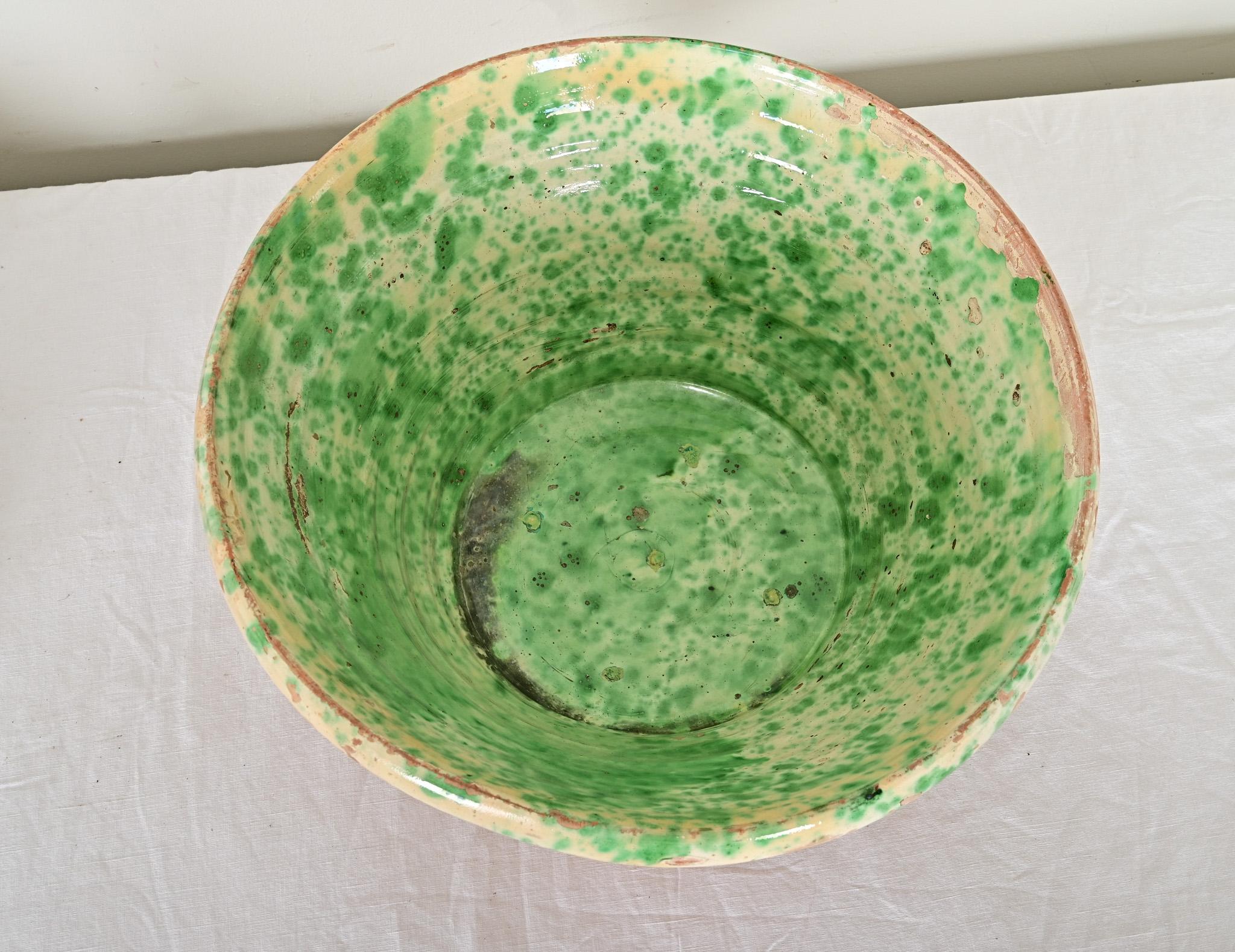 Un pintoresco cuenco de passata de la región italiana de Apulia, siglo XIX. El gran cuenco de terracota presenta un vidriado en efecto esponja de color verde brillante sobre un engobe amarillo mantecoso en el interior y está sin decorar en el