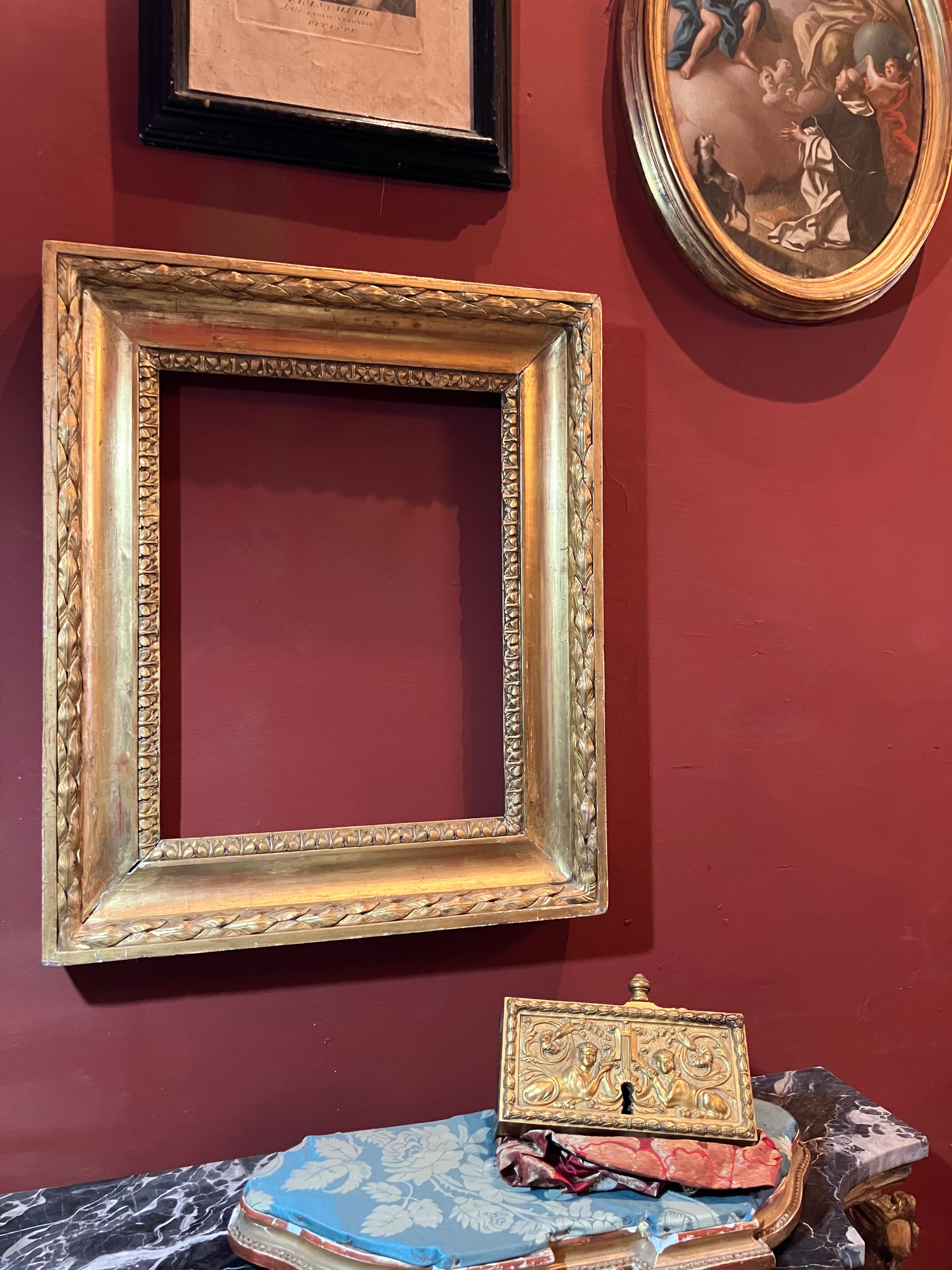 Elegant Italian Empire period gilt wood frame crafted in Tuscany, dating from the early 19th century. This richly carved piece features wide bands with deep laurel leaf decoration, symbol of triumph and eternity, finely executed and entirely gilded
