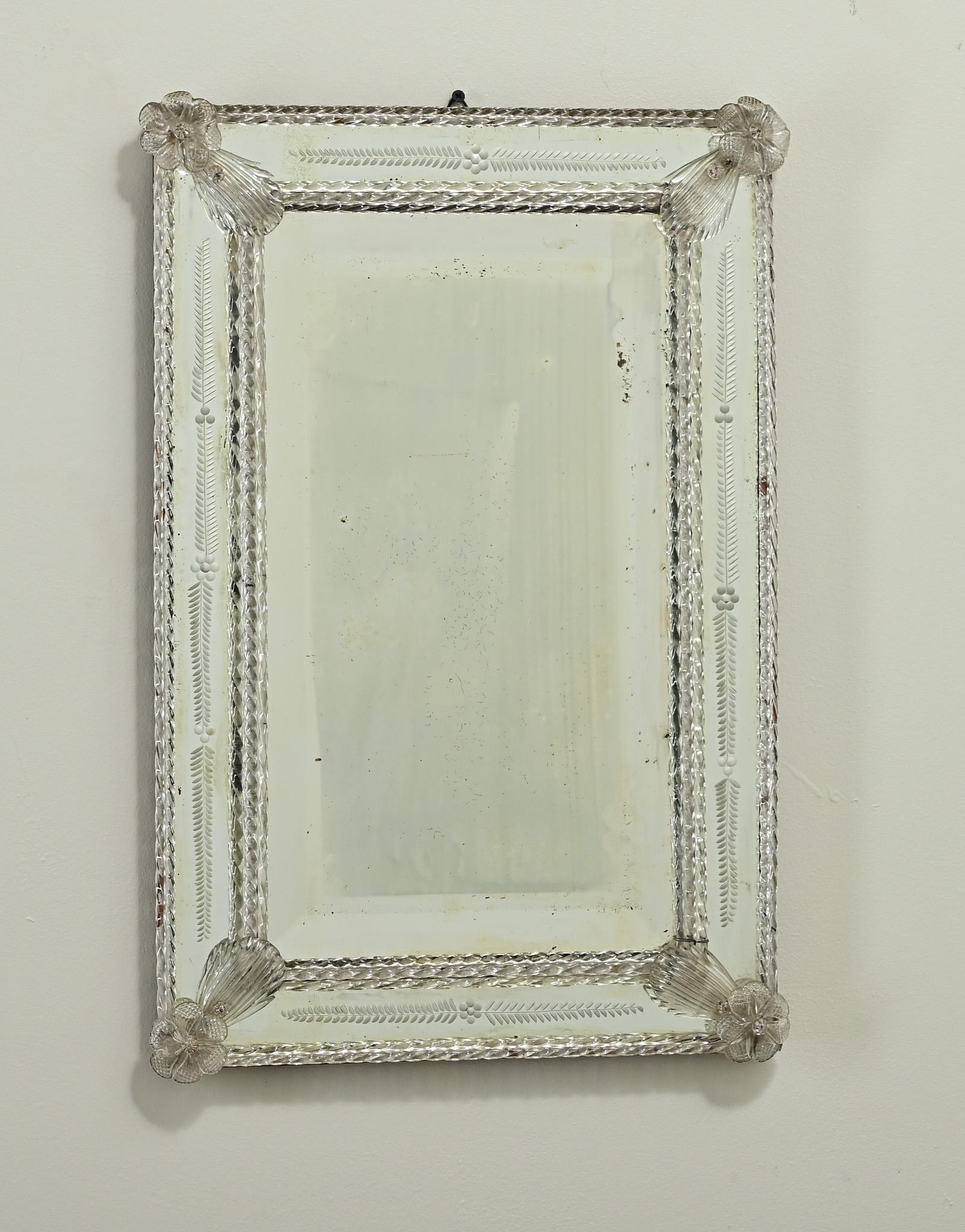 The frame of this unique Venetian mirror from Murano, Italy has beautiful floral etchings and hand blown glass appliqués. Inside the frame is the original hand cut beveled mirror plate with light foxing. Be sure to view the detailed images to get a