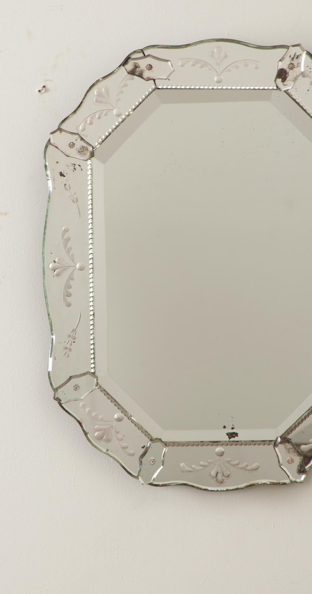 The frame of this unique Italian octagon shaped mirror features beautiful floral etchings. Inside the mirrored frame is a hand cut beveled mirror plate. Foxing is found throughout this fixture, typical of a mirror of this age. The whole is fixed on