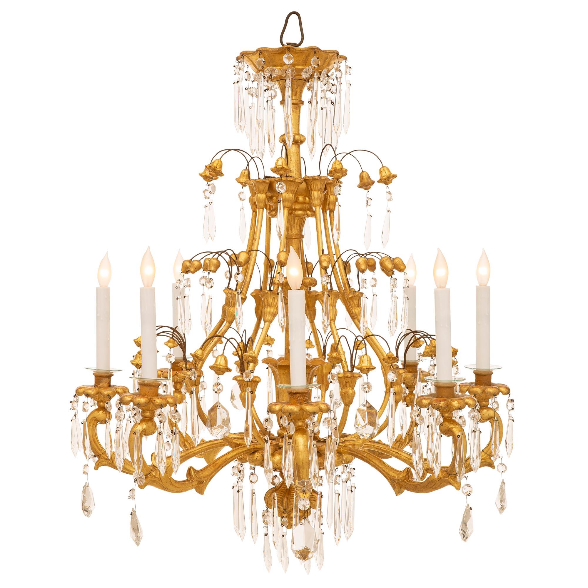 A beautiful and extremely decorative Italian 19th century Venetian st. giltwood and crystal chandelier. The eight arm chandelier is centered by lovely and most unique bottom foliate finial with prism cut crystal pendants and fine reeded designs.