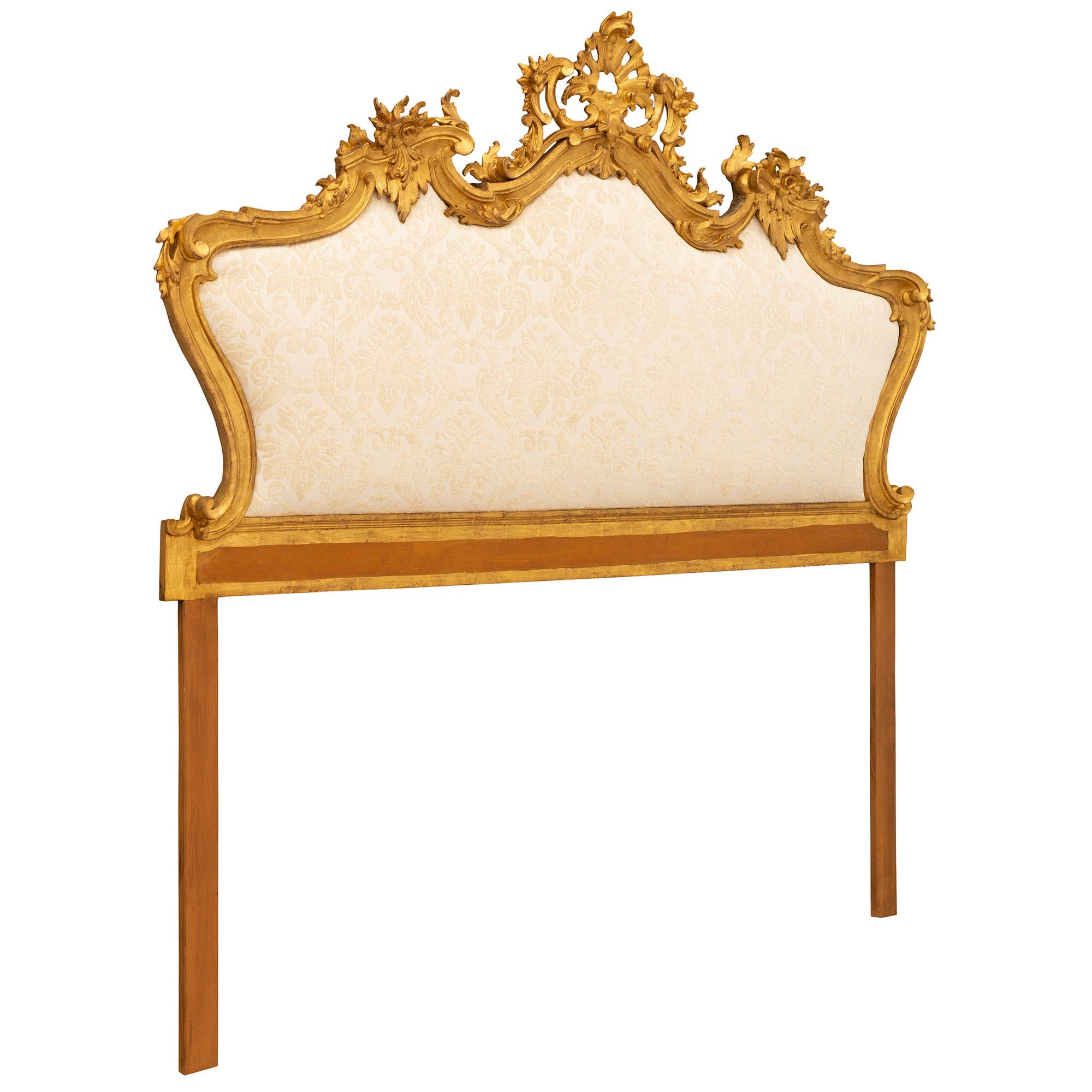 A beautiful and extremely decorative Italian 19th century Venetian st. giltwood and polychrome headboard. The upholstered headboard is framed within a wrap around mottled border and a lovely polychrome band at the base. The striking top crown