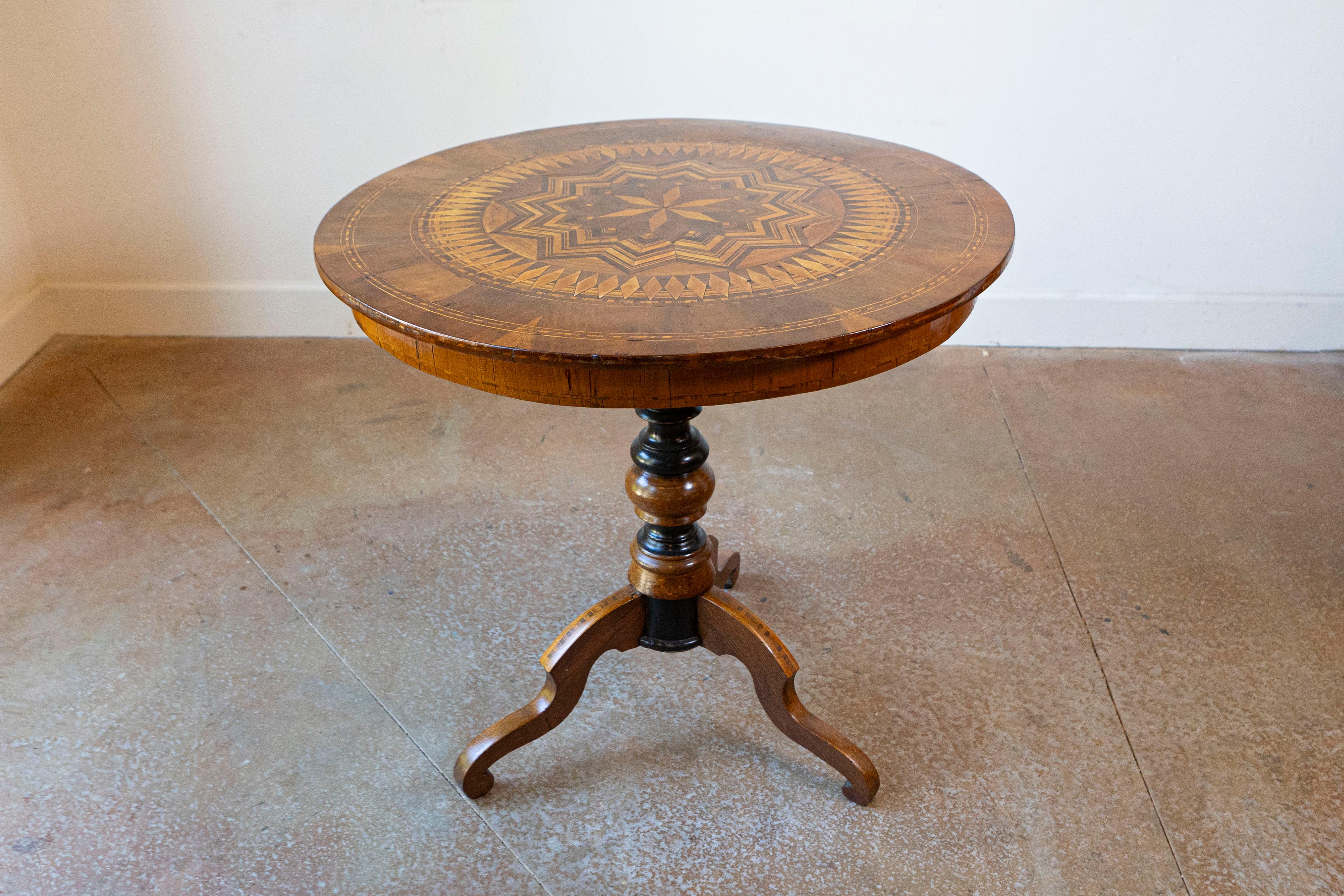 Italian 19th century marquetry walnut and birch center table with marquetry top, geometric motifs including radiating stars and diamonds. Exuding an air of timeless elegance, this Italian 19th century marquetry center table invites you to immerse