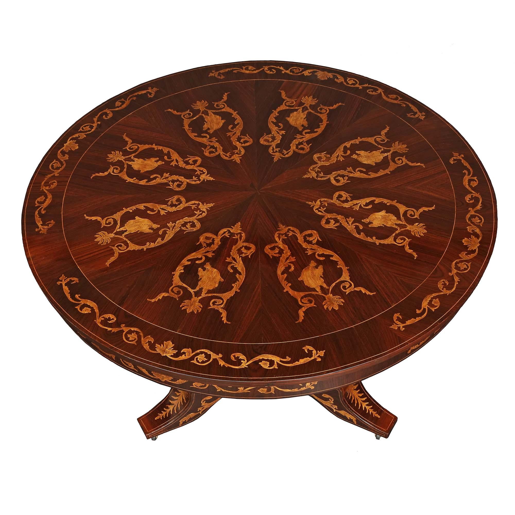 An outstanding Italian 19th century walnut and fruitwood inlaid center table. The circular table is raised by casters leading up three supports to the triangular tapered central fut with concave sides and rich fruitwood inlays of palmettes and