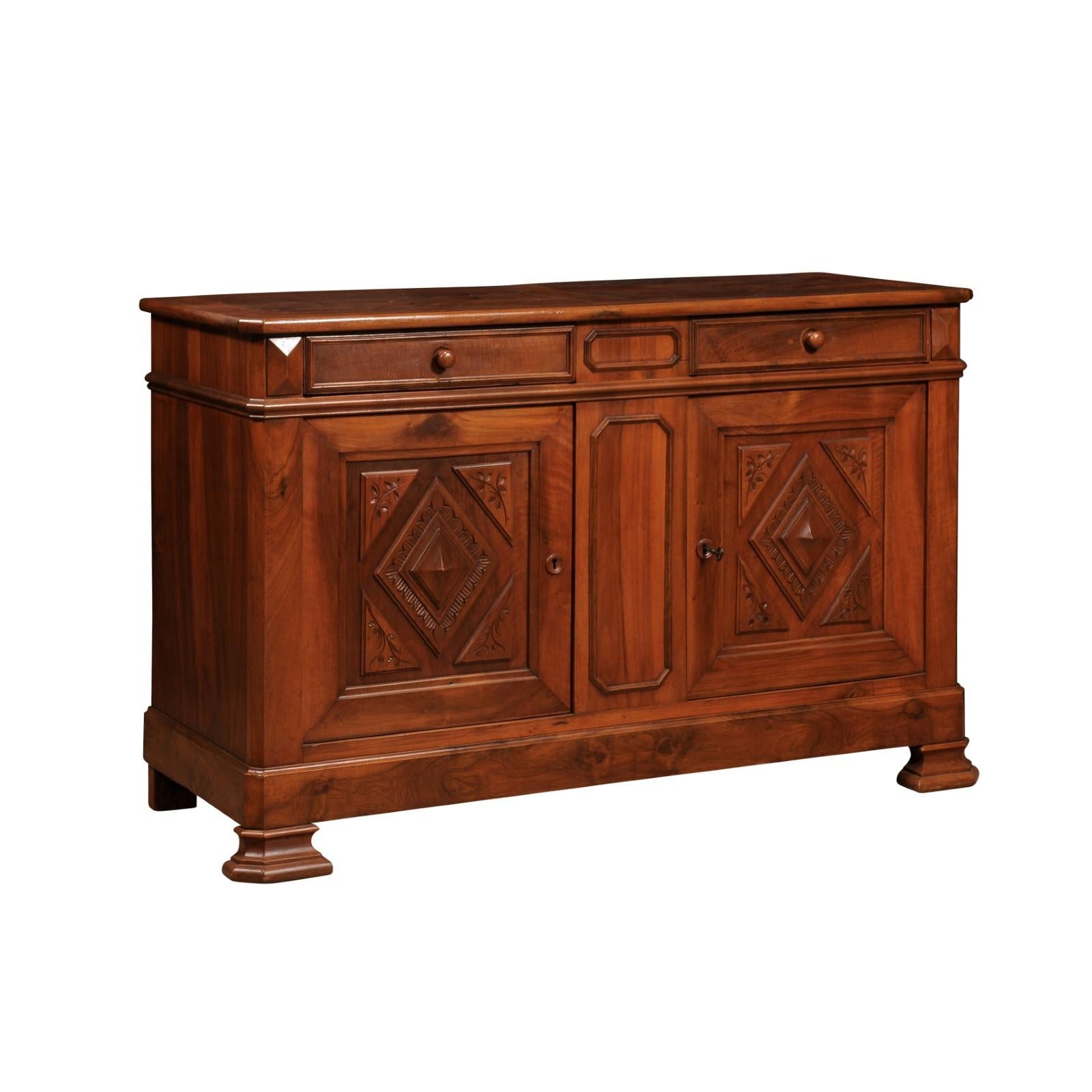 An Italian walnut buffet from the 19th century with two drawers over two doors, carved diamonds and floral motifs. This 19th-century Italian walnut buffet exudes classic elegance and refined craftsmanship. The piece features a harmonious blend of