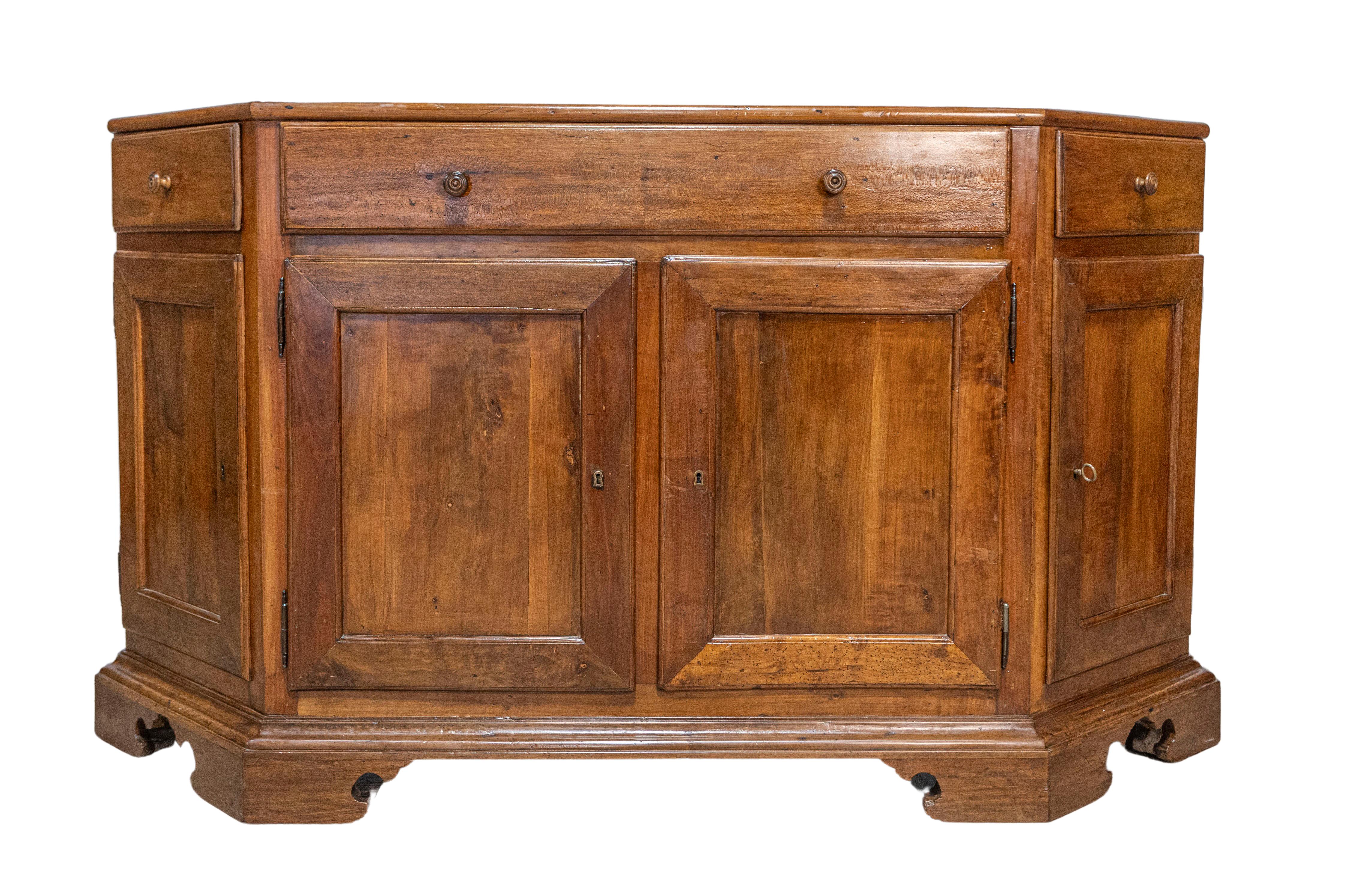 An Italian walnut credenza from the 19th century with three drawers over four doors and canted sides. This elegant 19th-century Italian walnut credenza combines functional design with traditional craftsmanship. Featuring three drawers over four