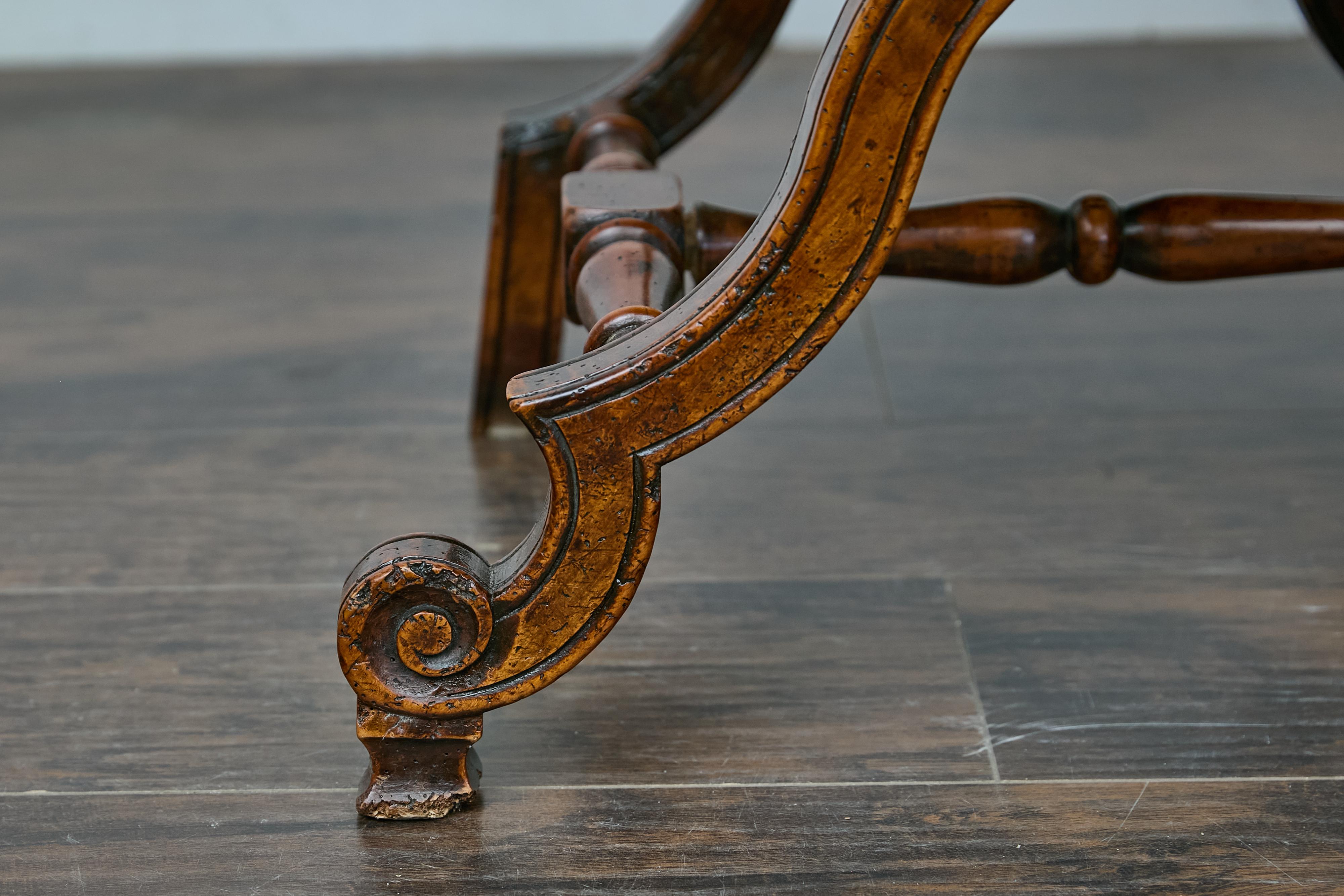 Poltrona italiana in noce Curule del XIX secolo con seduta e schienale imbottiti e base intagliata a X. Questa poltrona italiana in noce Curule del XIX secolo dona un'accattivante miscela di eleganza classica e raffinata maestria a qualsiasi
