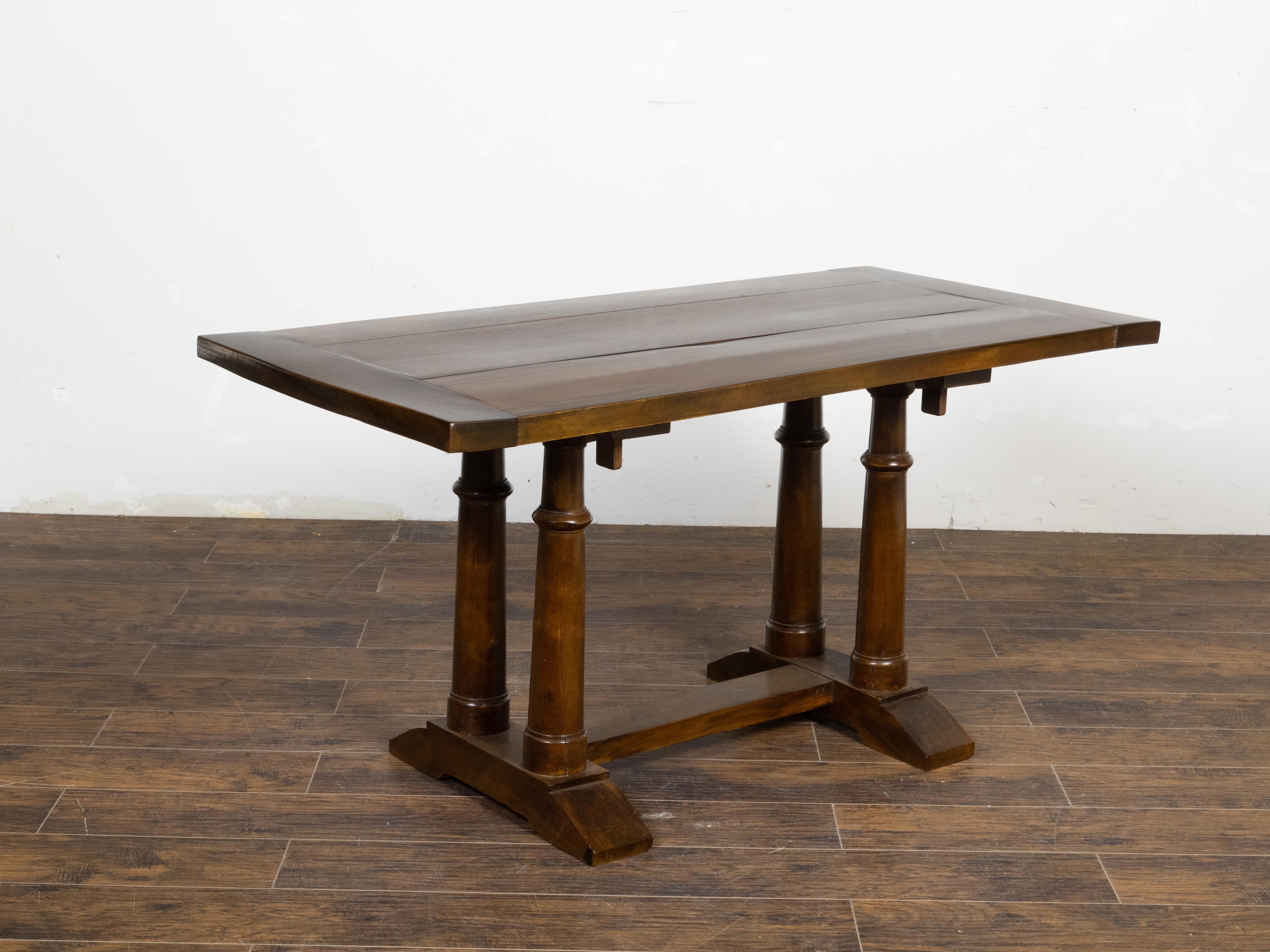 An Italian walnut trestle table from the 19th century, with column shaped legs. Created in Italy during the 19th century, this walnut table features a rectangular planked top with darker boards on the sides, sitting above a trestle base. Four