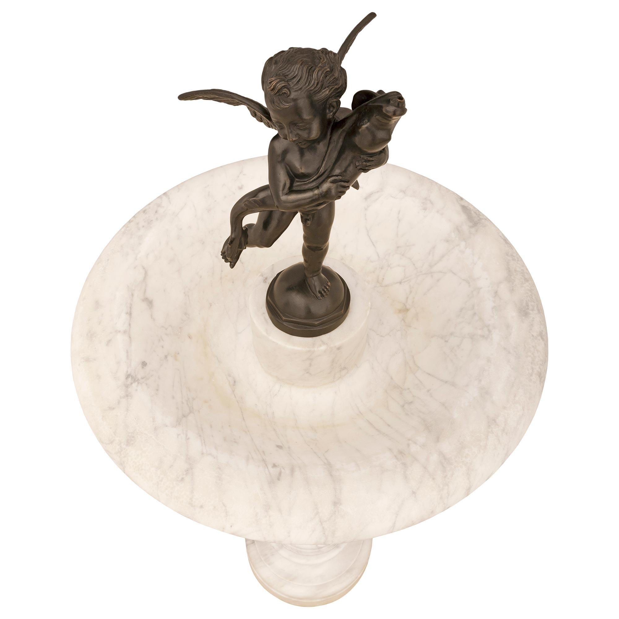 A sensational and high quality Italian 19th century white Carrara marble and patinated bronze fountain. The fountain is raised by a circular base below the elongated baluster shaped central column support. Above and at the center of the bowl is a