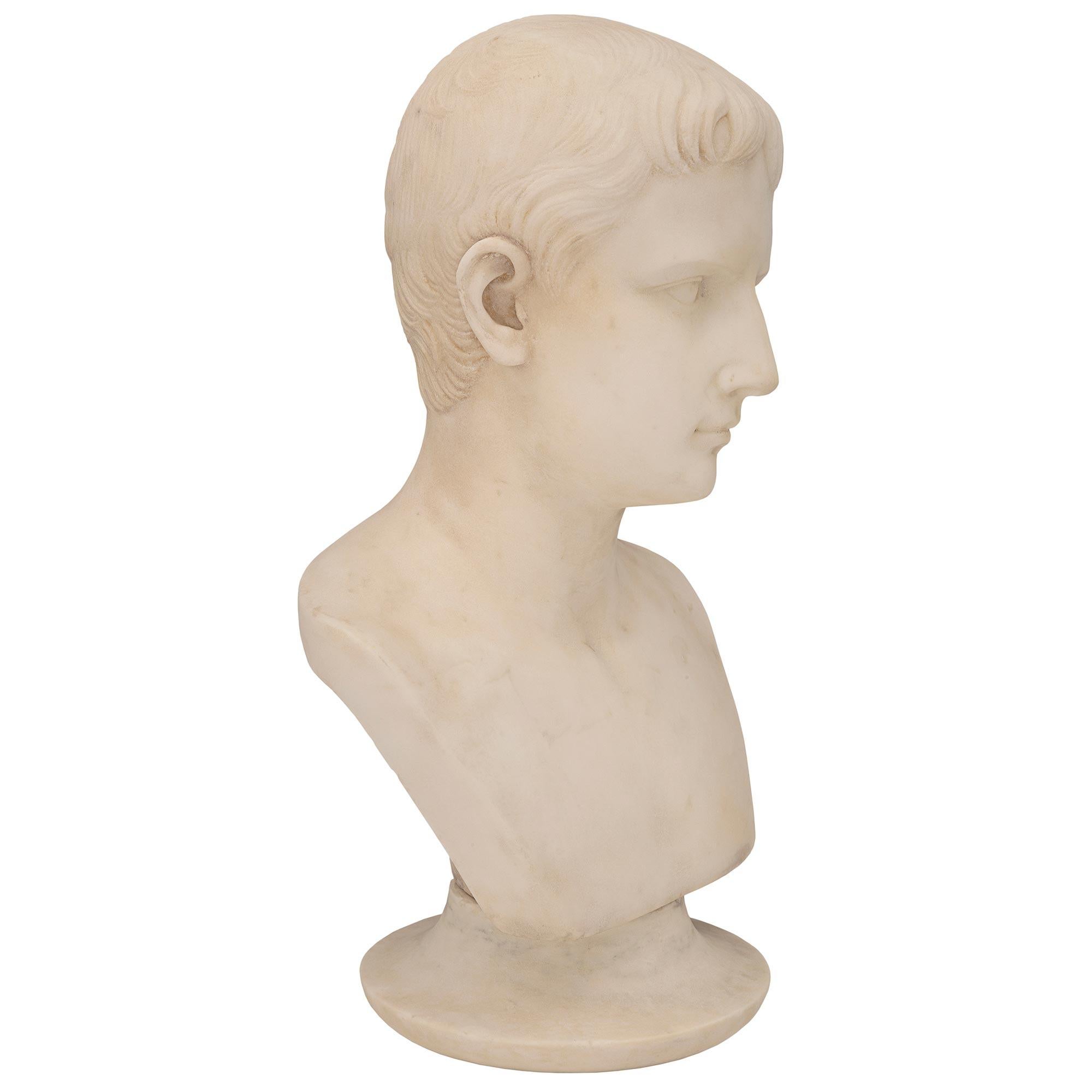 A handsome and finely detailed Italian 19th century white Carrara marble bust of a young August of Prima Porta. The bust of Augustus, also known as Julius Caesar, is raised by a mottled circular base. Above is the wonderfully executed bust of