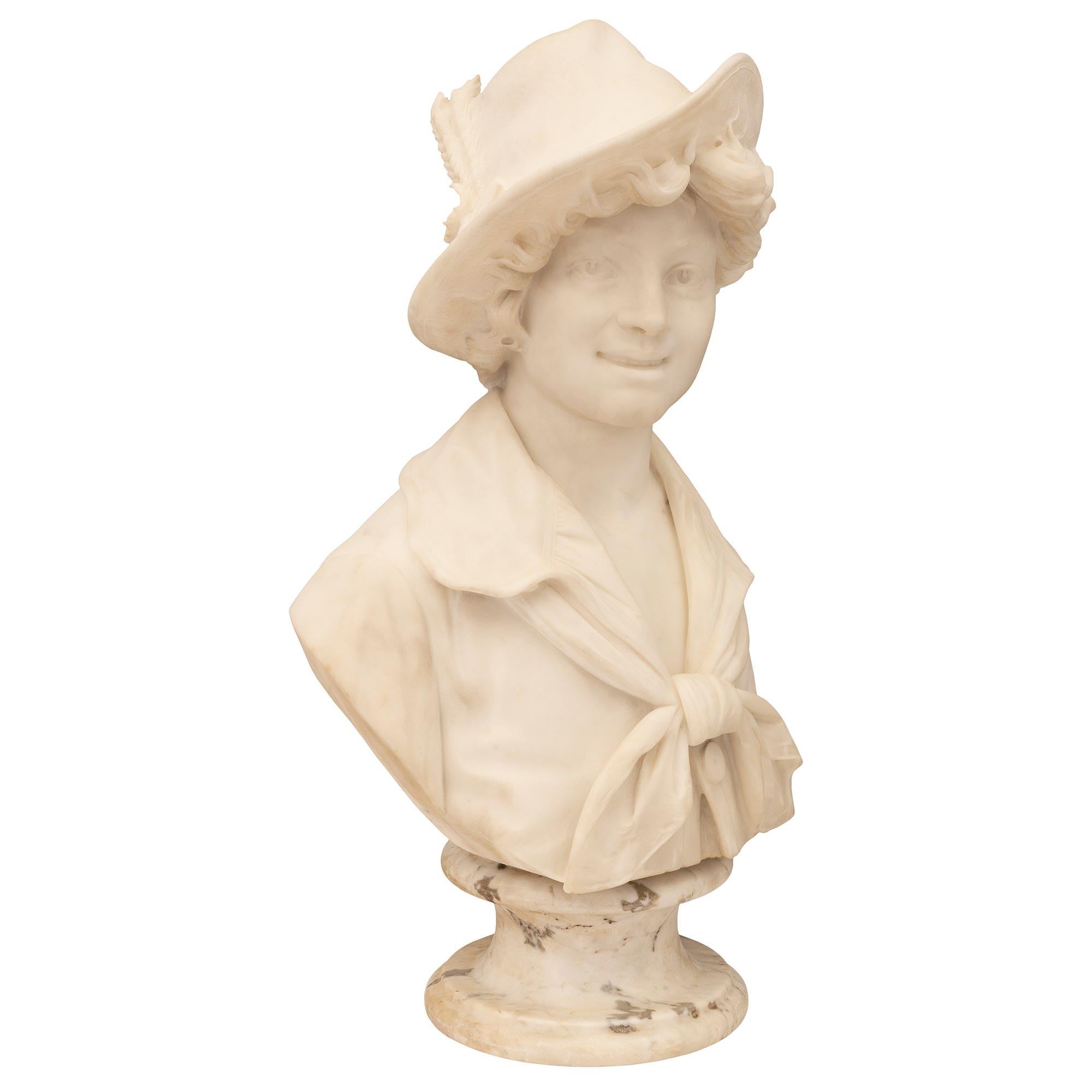 A beautiful and very high quality Italian 19th century white Carrara marble bust of a young boy. The bust is raised by an elegant circular socle shaped pedestal support with a fine mottled border. The richly sculpted bust above depicts a charming