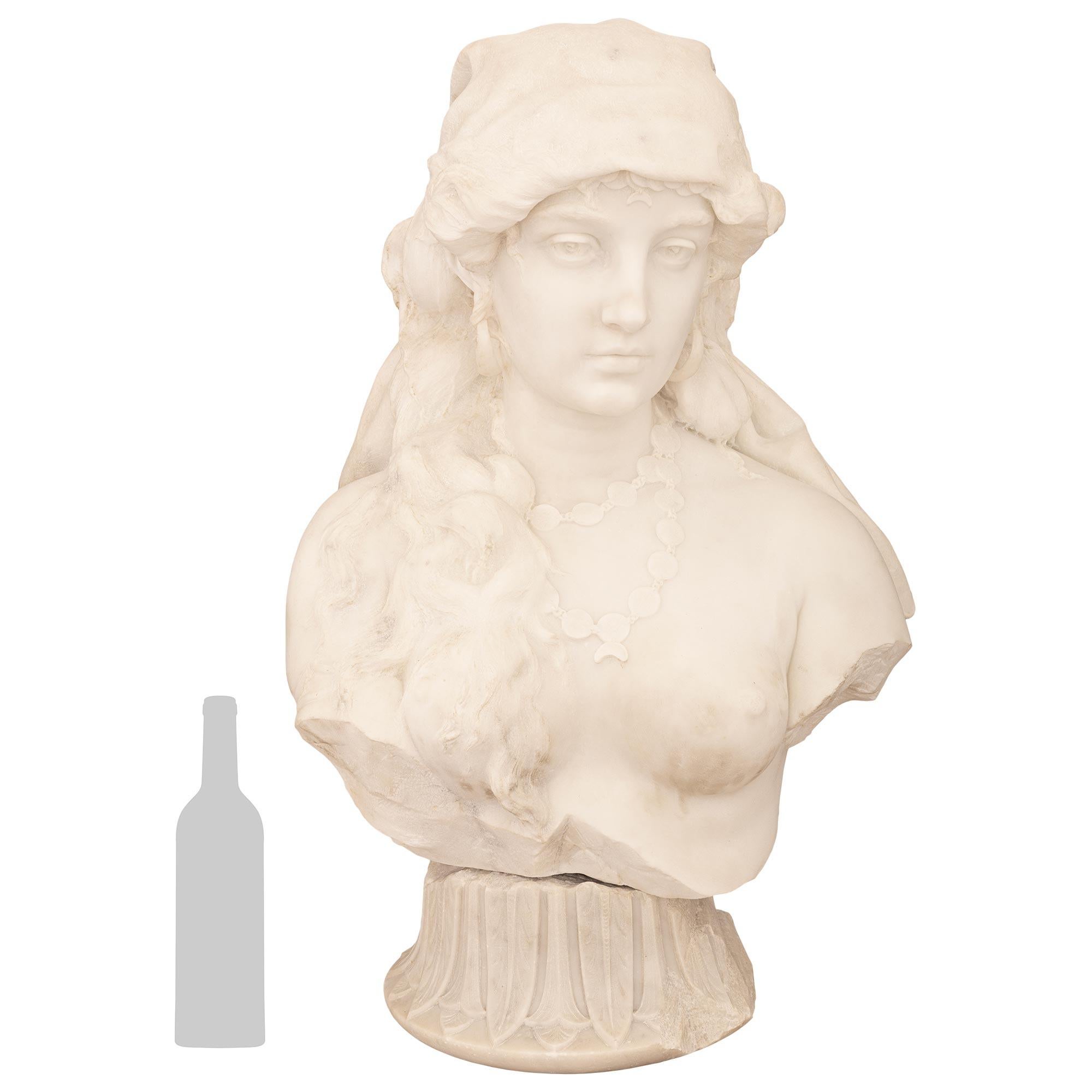 Un busto in marmo bianco di Carrara del XIX secolo, di alta qualità, firmato da Giovanni Sartorio. Questo busto davvero meraviglioso di una bella donna è sollevato e sostenuto sul suo piedistallo originale a socle. Il piedistallo circolare a socle è