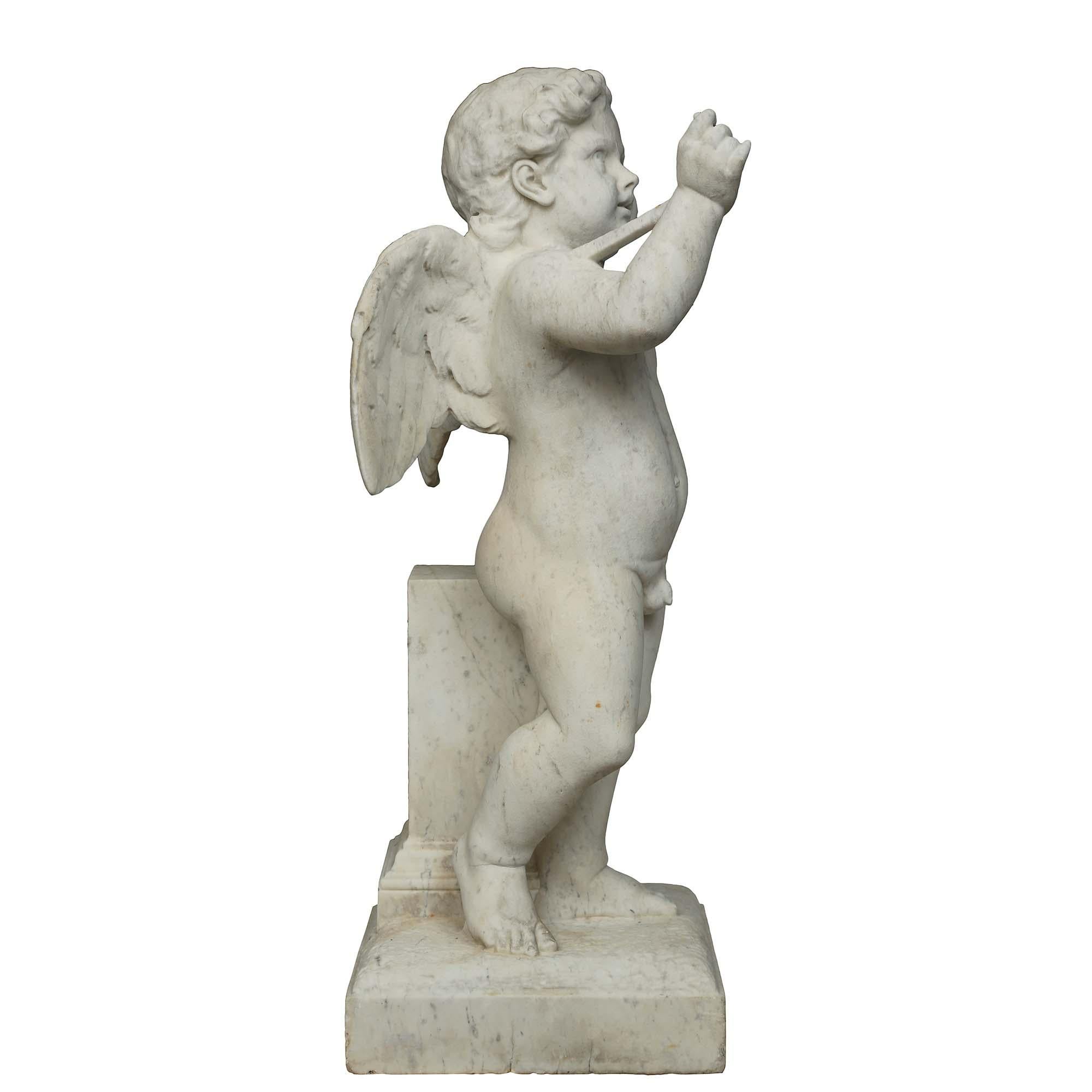 A charming Italian 19th century white Carrara marble cherub fountain. The fountain is raised by a square base with terrain-like design below the cherub leaning on an architectural element. The nude winged cherub has one hand in the air and an