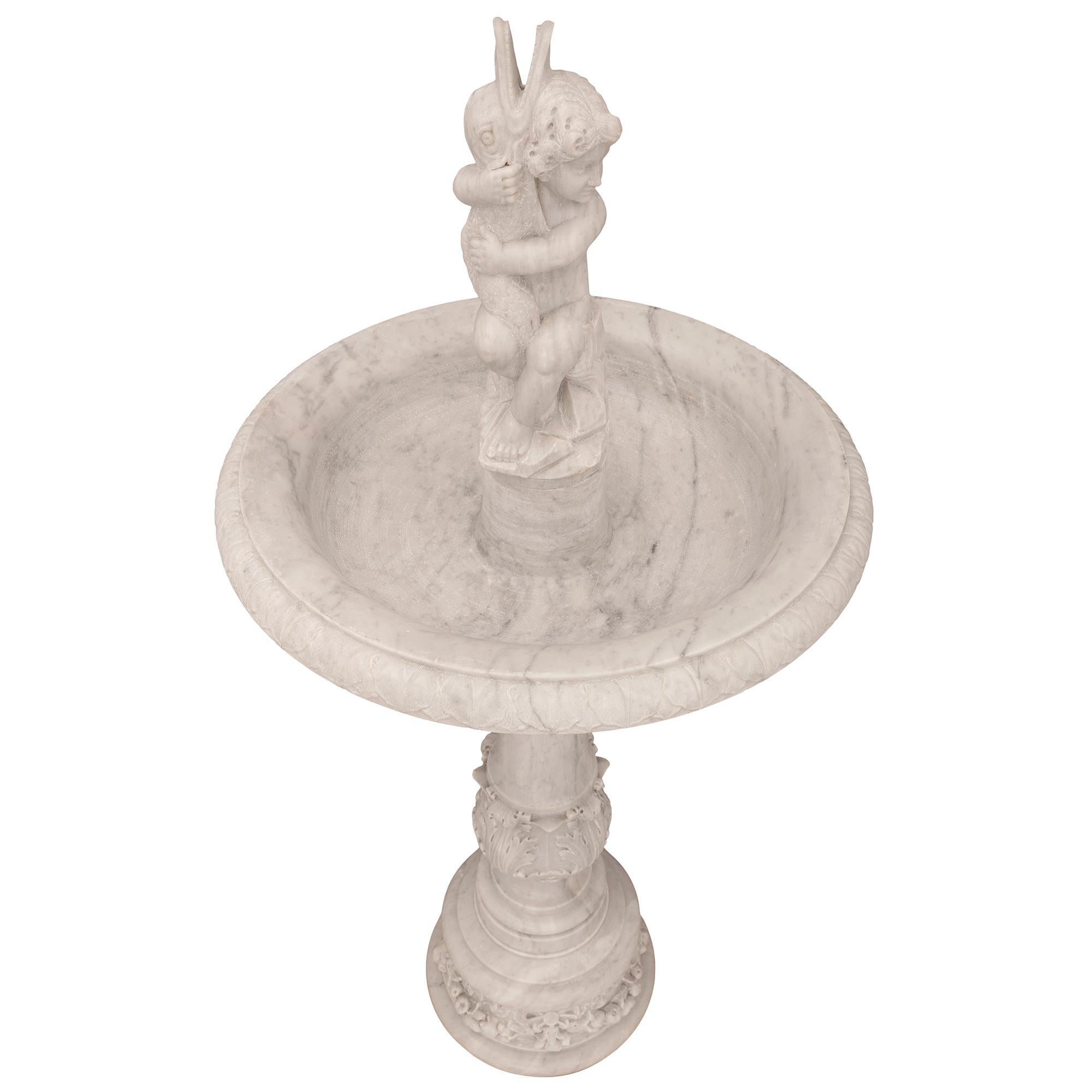 A beautiful and most elegant Italian 19th century white Carrara marble fountain. The fountain is raised by a circular base with a fine mottled border and exquisite richly sculpted blooming flowers and ripe fruit tied with wonderful flowing ribbons.