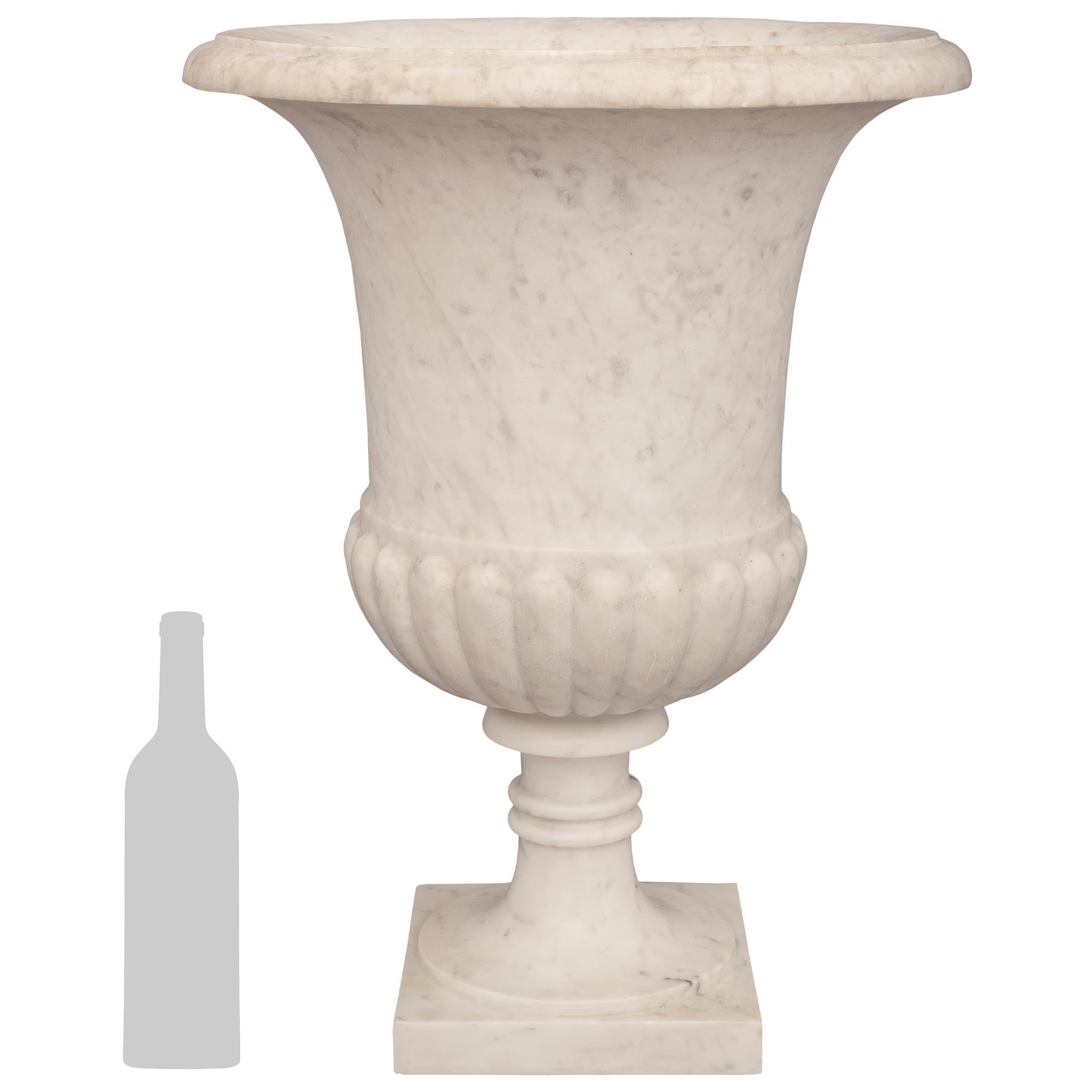 Eine beeindruckende und äußerst dekorative italienische Medici-Vase aus weißem Carrara-Marmor des 19. Jahrhunderts. Dieses schöne Pflanzgefäß wird von einem glatten, runden Sockel mit zwei zentralen Bändern getragen und steht auf einem quadratischen