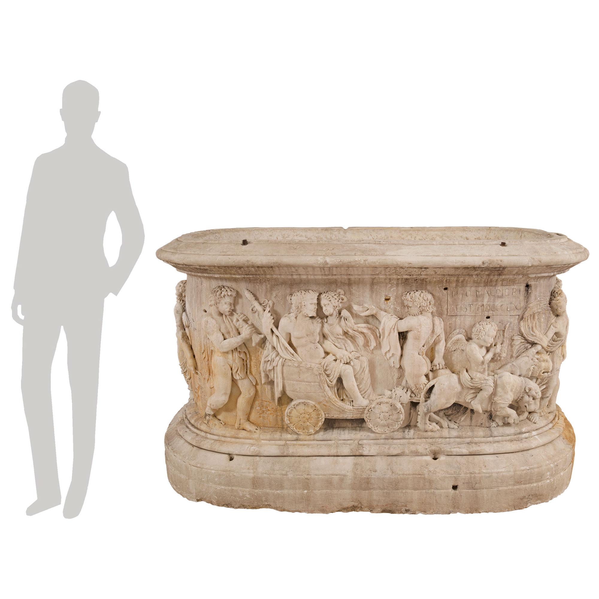 A truly spectacular and monumentally scaled Italian 19th century Neo-Classical st. white Carrara marble planter of the Marriage of Bacchus and Ariadne. The statement making planter is raised by a striking thick mottled base with a fine wrap around