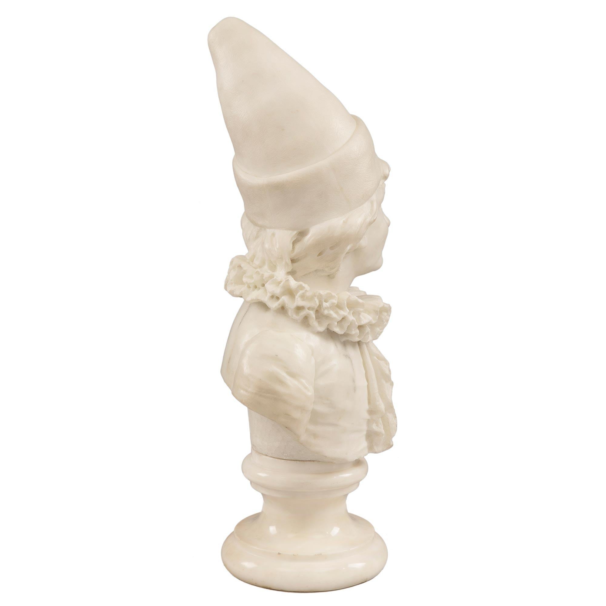 A charming and well executed Italian 19th century White Carrara marble signed bust of Pierrot. The young Pierrot is raised by its original circular mottled socle base. Pierrot, having a wonderful expression on his face, is wearing a detailed tudor