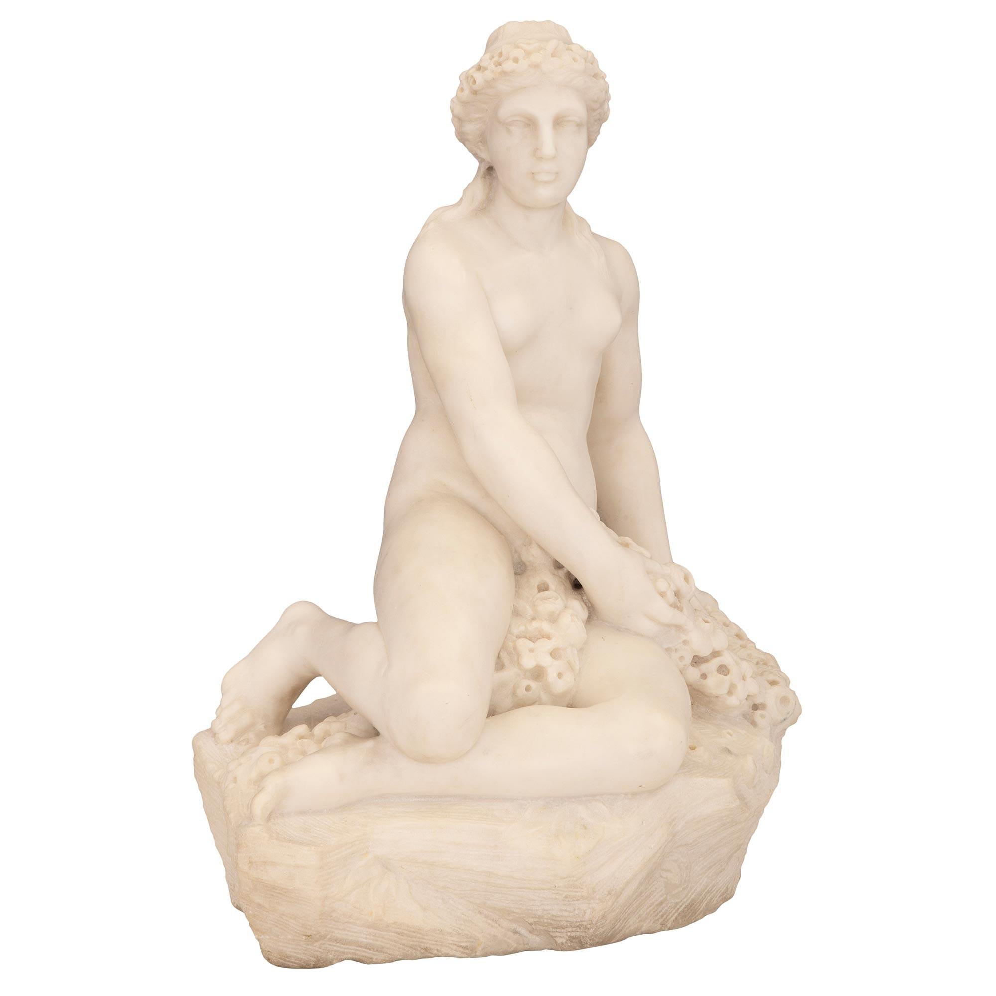 Statue en marbre blanc de Carrare de très haute qualité, datant du 19e siècle, originaire d'Italie. Cette statue merveilleusement exécutée représente une belle jeune femme assise sur un arbre taillé, avec un panier tressé rempli de fleurs