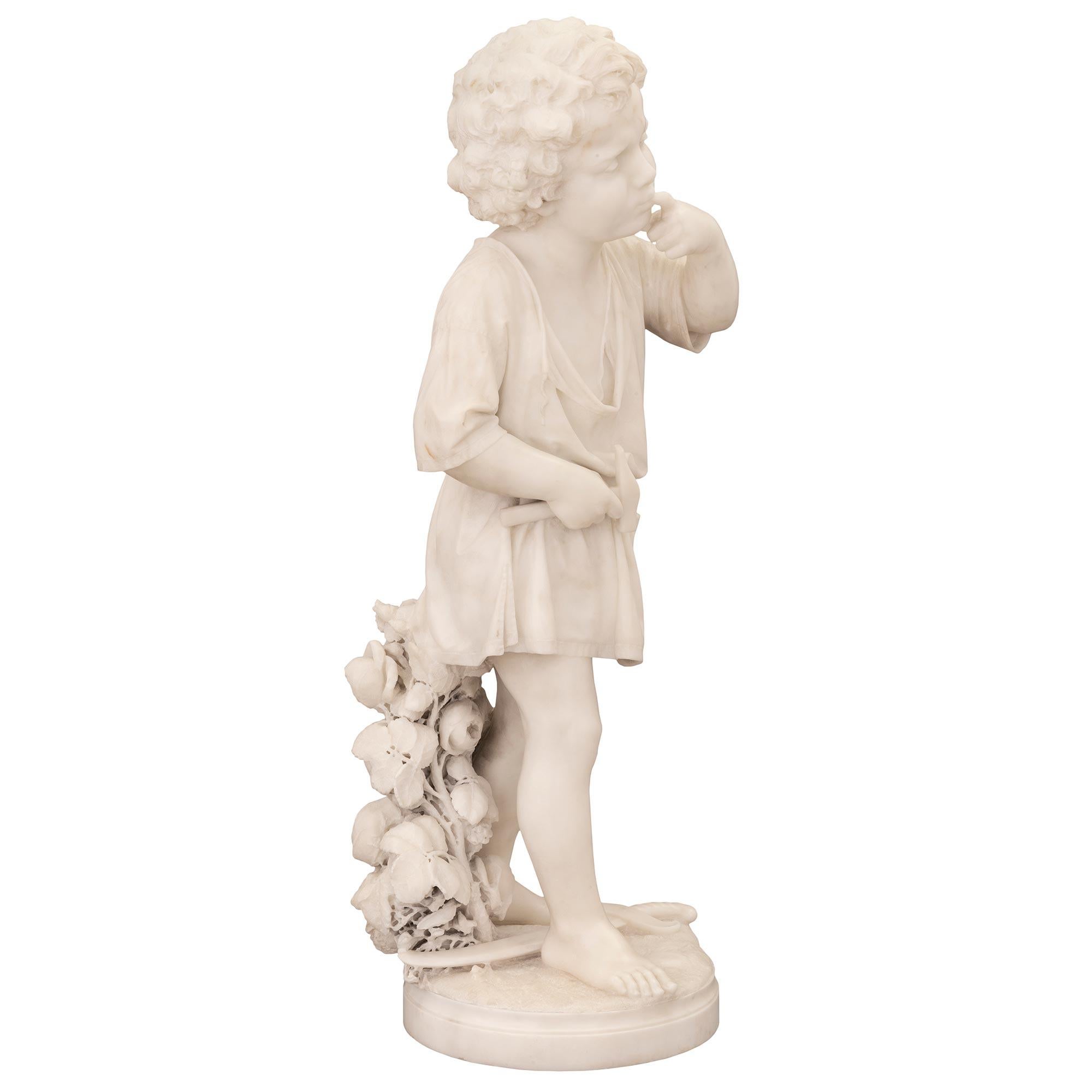 A stunning and very charming museum-quality Italian 19th century white Carrara marble statue of a boy signed Ugo Zannoni Milano 1876. The statue of a young boy having hit his finger with a hammer is raised by a circular base with a fine mottled