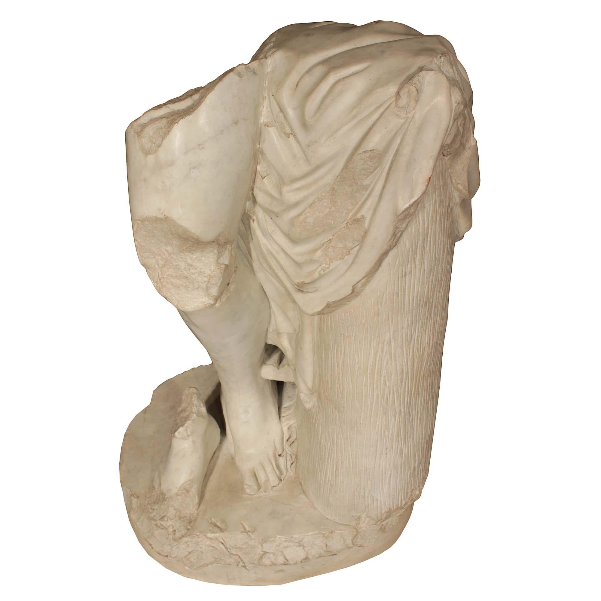 An exceptional and decorative and handsome 19th century Italian white Carrara marble statue. This spectacular marble fragment of a leg and feet, likely a classical figure donning a flowing cape, beside a column. All raised on a circular base.