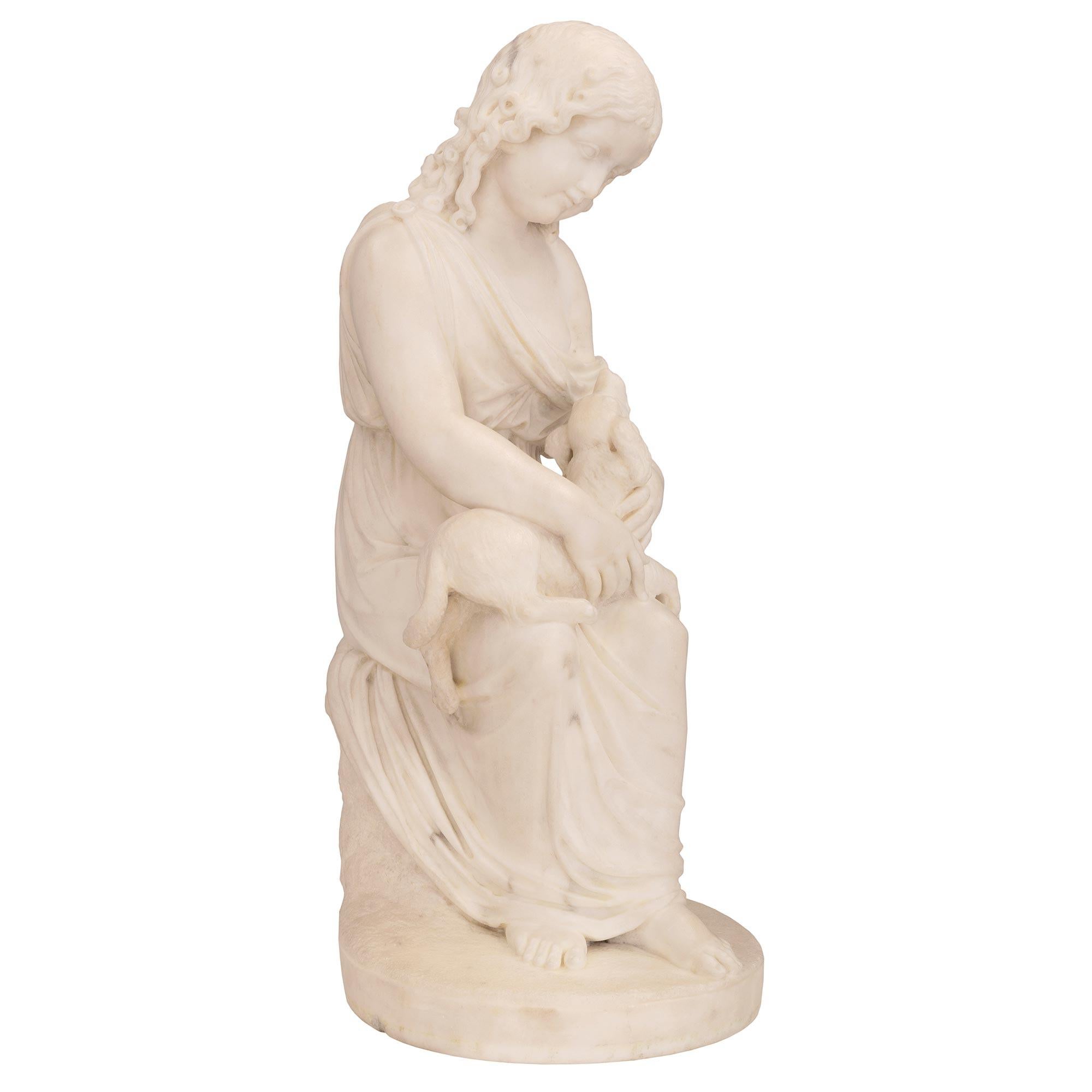 A wonderfully executed Italian 19th century white Carrara marble statue of a young girl with her dog. The statue is raised by a circular base with a fine ground-like design and a large rock at the back. The beautiful young girl is seated on the rock