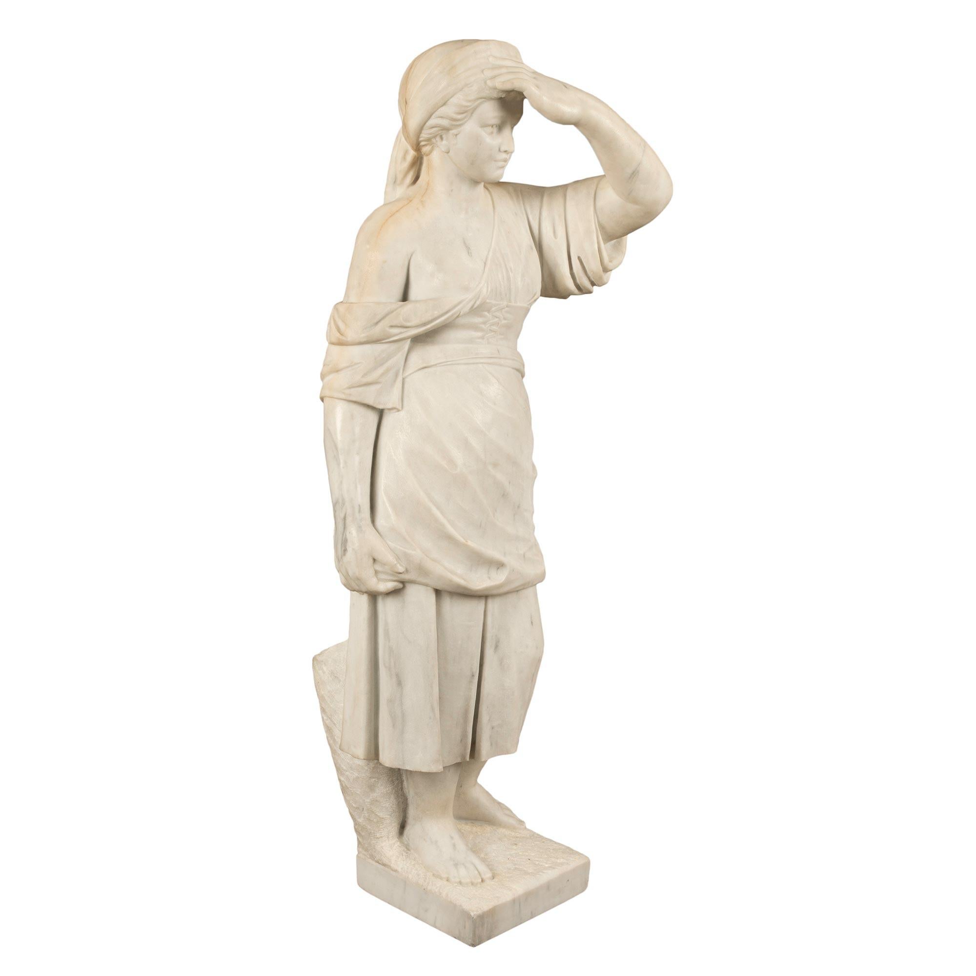 A beautiful Italian 19th century white Carrara marble statue of a young lady. The statue is raised by a square base with a tree stump at the back. The lovely young lady is wearing a wonderfully sculpted dress falling off one shoulder. She holds her