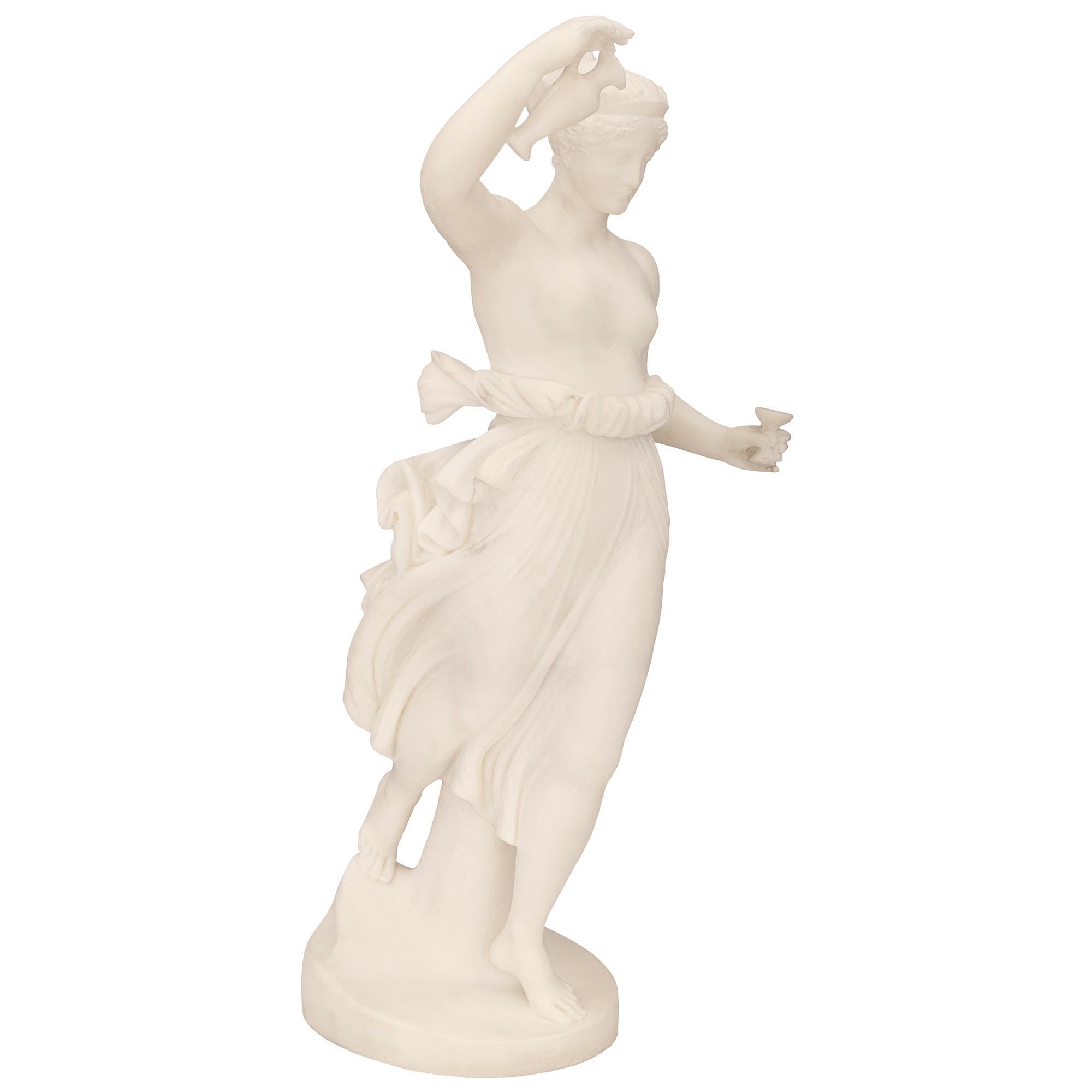 A beautiful and high quality Italian 19th century white Carrara marble statue of Hebe. The statue is raised by a circular base where the beautiful Hebe is standing barefoot in front of a tree trunk. She is wearing her hair in an updo and is draped