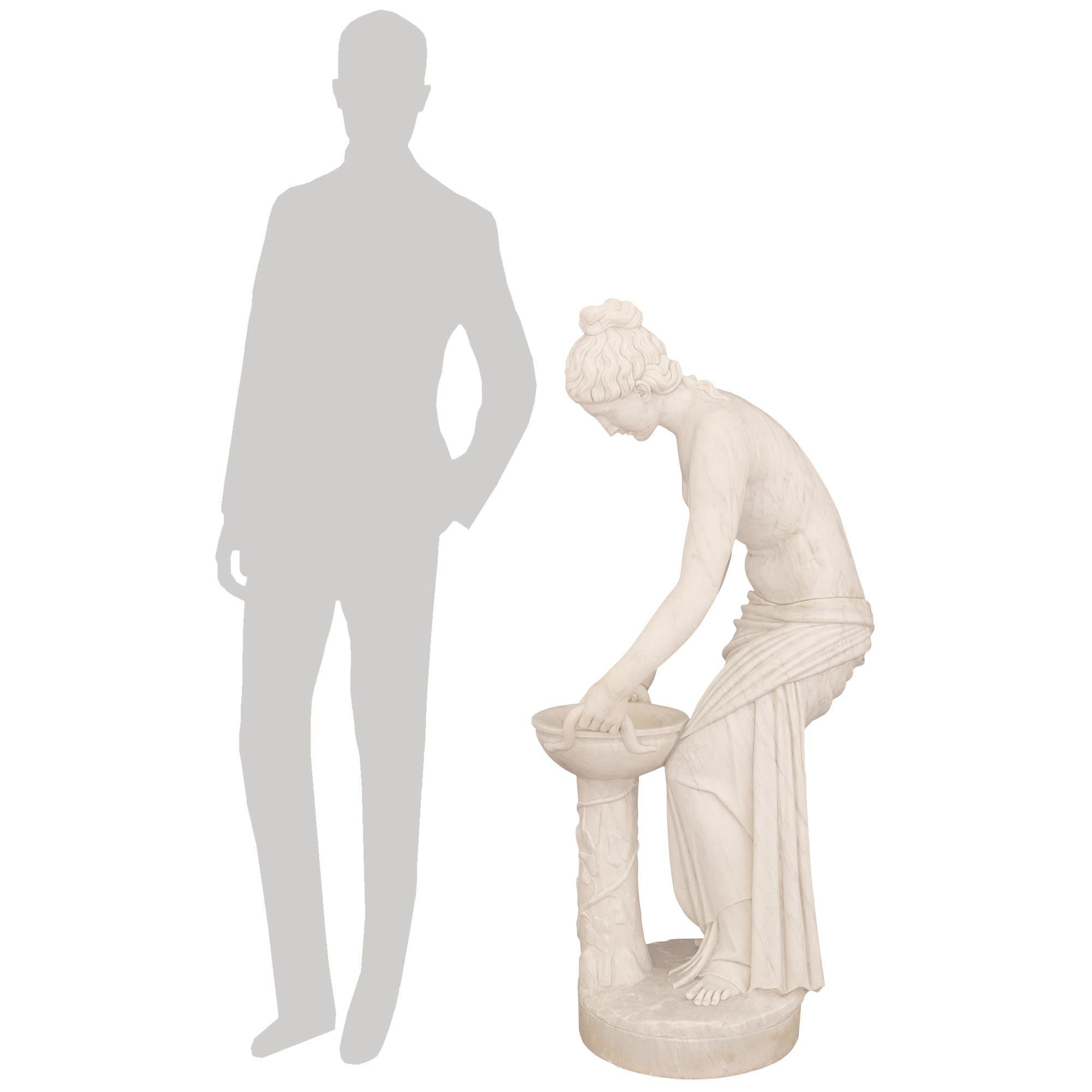 Una splendida statua in marmo bianco di Carrara del XIX secolo, finemente dettagliata, raffigurante Ebe. Questa splendida statua raffigura Ebe, la dea della giovinezza e figlia di Zeus ed Era. Hebe è in piedi su una base disegnata a terra mentre