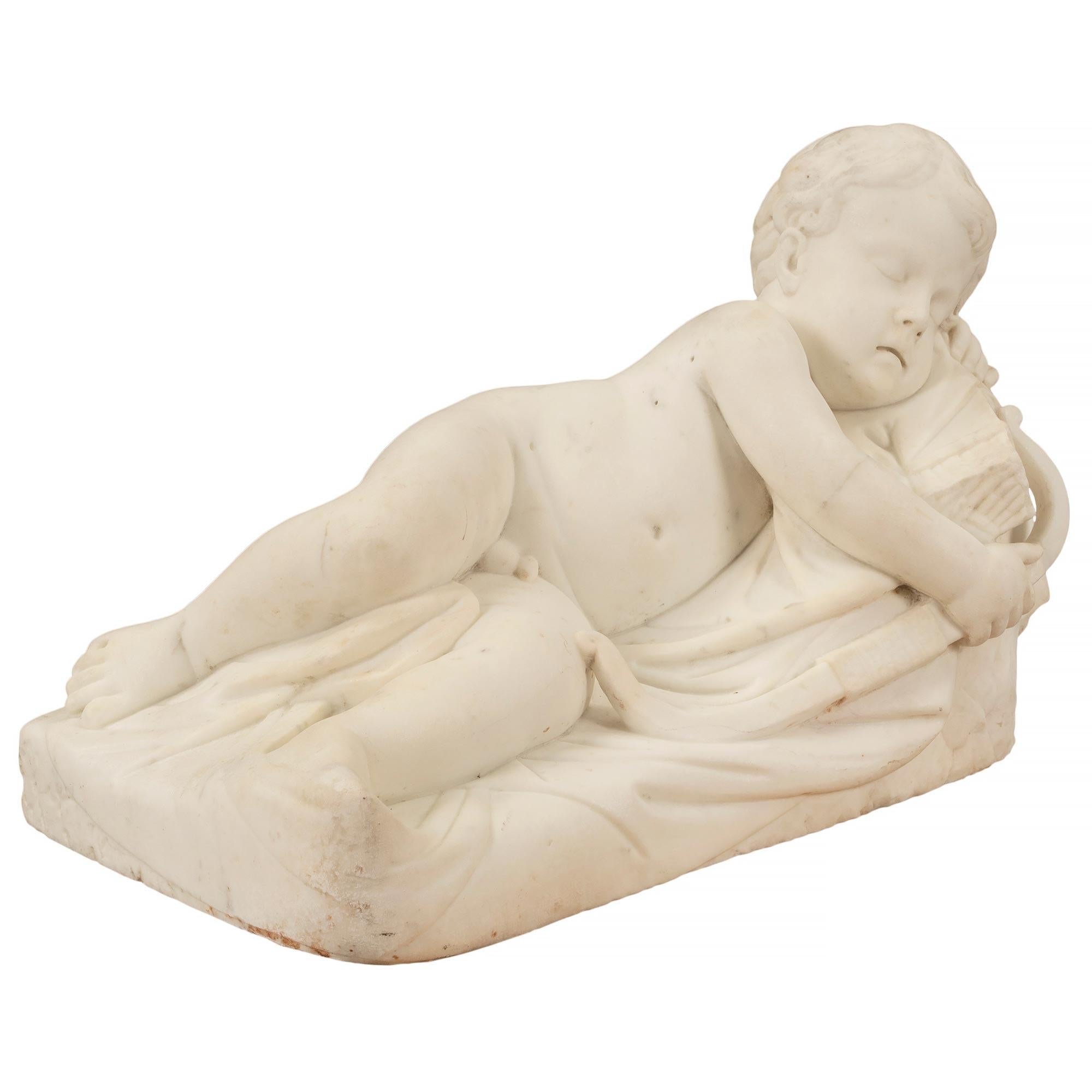 A charming Italian 19th century white Carrara marble statue of sleeping Cupid. The statue is raised by a terrain designed base where the richly sculpted Cupid sleeps. He lays on a wonderfully executed blanket with his head resting gently on a rock.