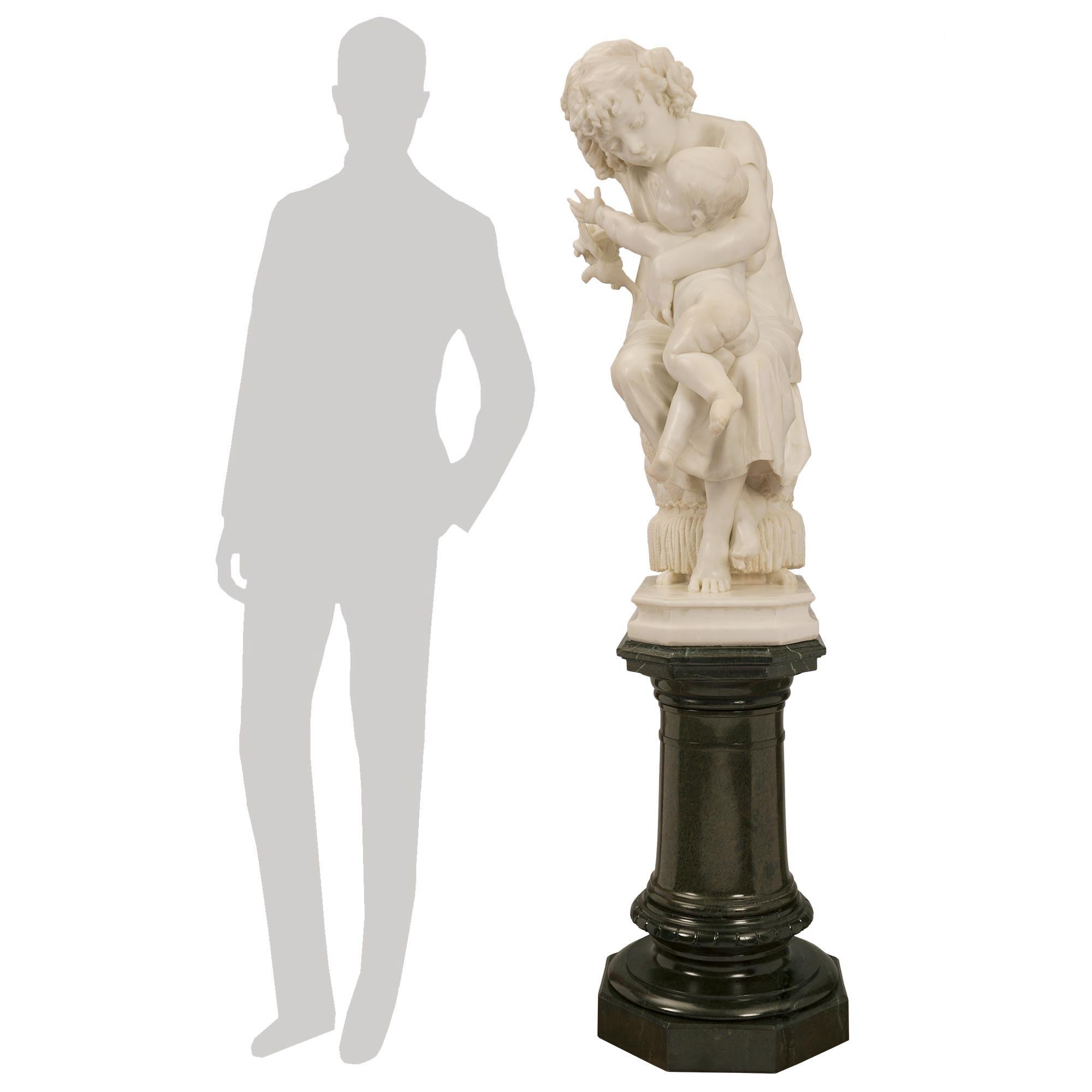 Superbe statue italienne du XIXe siècle en marbre blanc de Carrare sur son piédestal pivotant d'origine en marbre Vert de Patricia. La statue représente une belle jeune fille qui console son petit frère après qu'elle lui ait pris un oiseau avec