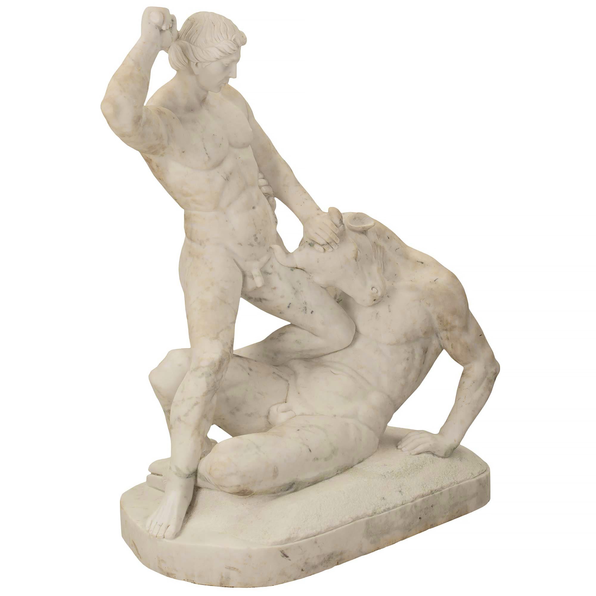 A very handsome Italian 19th century white Carrara marble statue of Theseus and the Minotaur. The statue is raised on an oval base with the Minotaur lying in defeat as Theseus is poised to strike the monster. The story of Theseus and the Minotaur