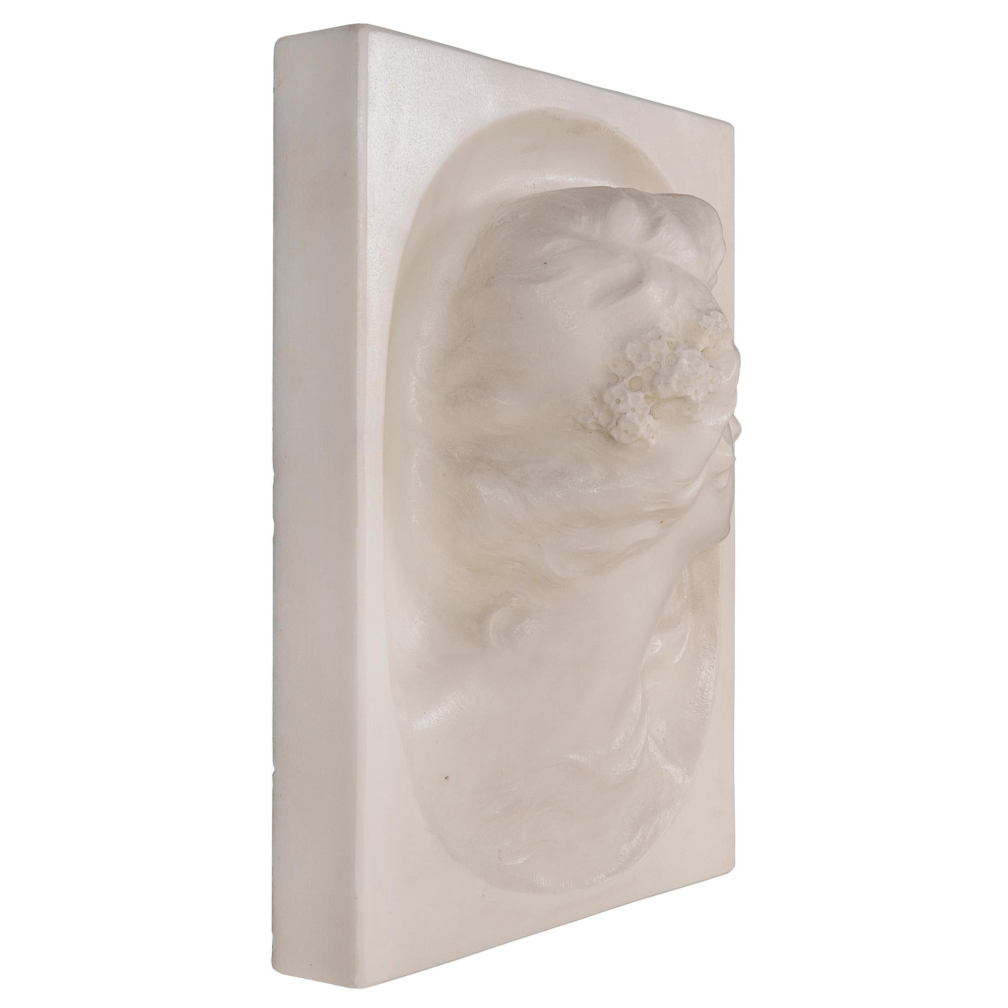 A striking and most decorative Italian 19th century white Carrara marble wall plaque. The rectangular plaque is centered by a beautiful richly sculpted maiden at the center with charming flowers in her hair. She looks to her left while her hair is
