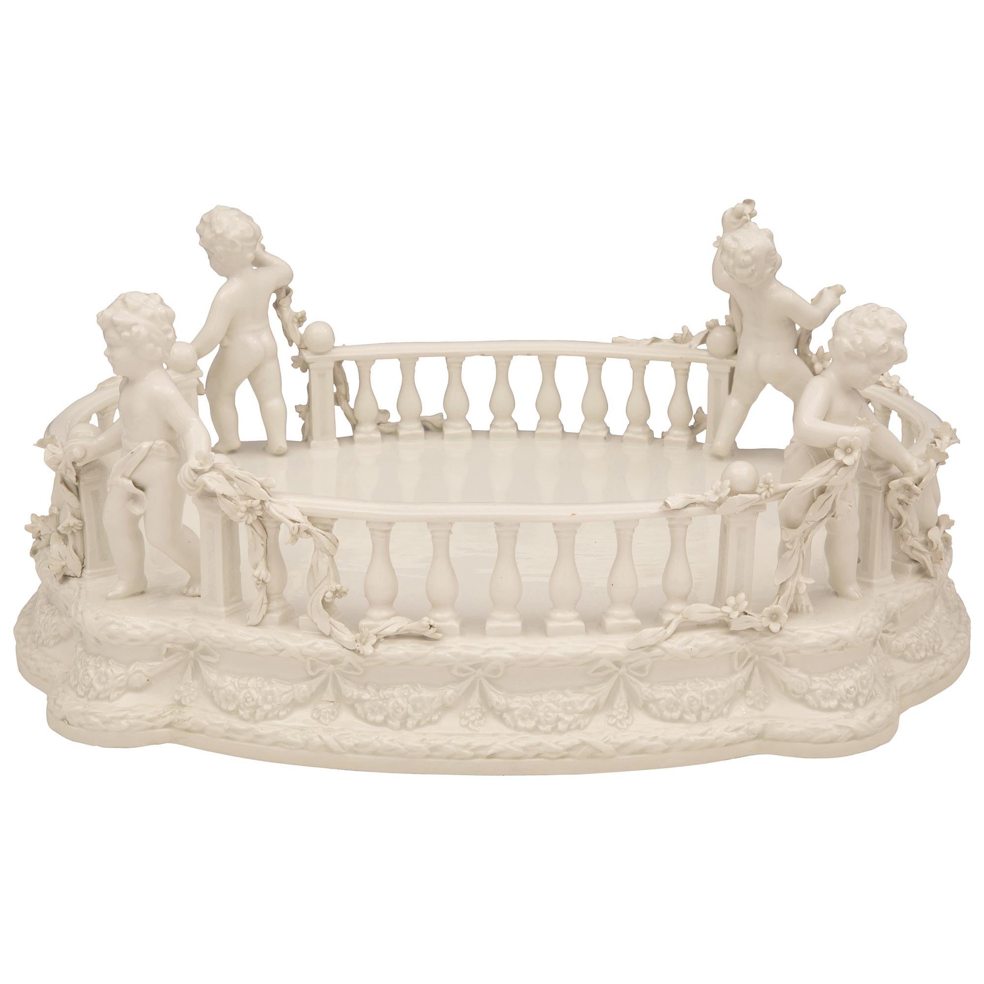 Charmant centre de table en porcelaine blanche italienne du XIXe siècle, signé Bassano. Le centre de table est surélevé par une jolie base festonnée, avec des bandes de lauriers berry finement nouées et de belles guirlandes florales qui s'étendent