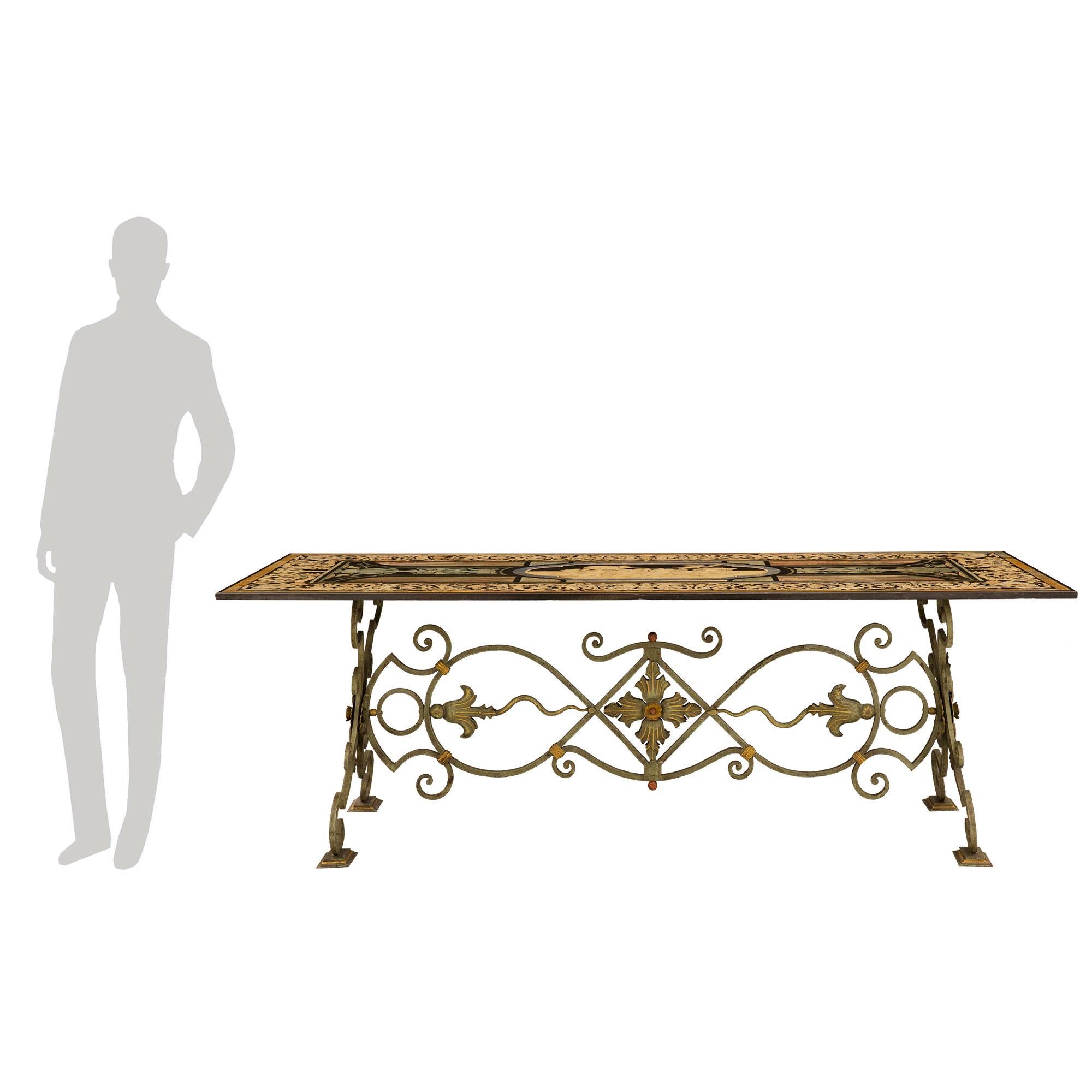 Superbe table de salle à manger italienne du XIXe siècle en fer forgé patiné vert-de-gris, doré et Scagliola. La table est soutenue par une magnifique base en fer forgé patiné vert-de-gris avec des accents dorés, des mouvements à volutes frappants
