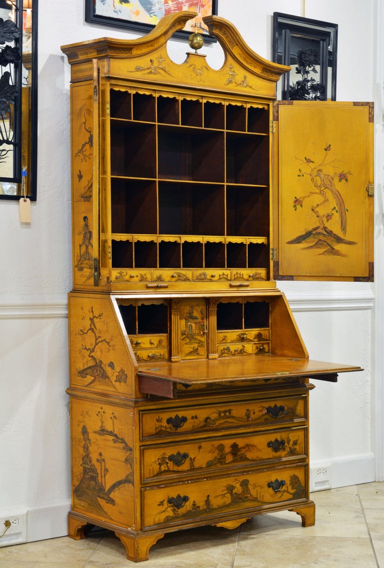 This charming Italian neoclassical style chinoiserie decorated secretary desk features an arched open pediment centering a brass finial above two mirrored arched doors opening up to an interior fitted with large and small compartments. The lower