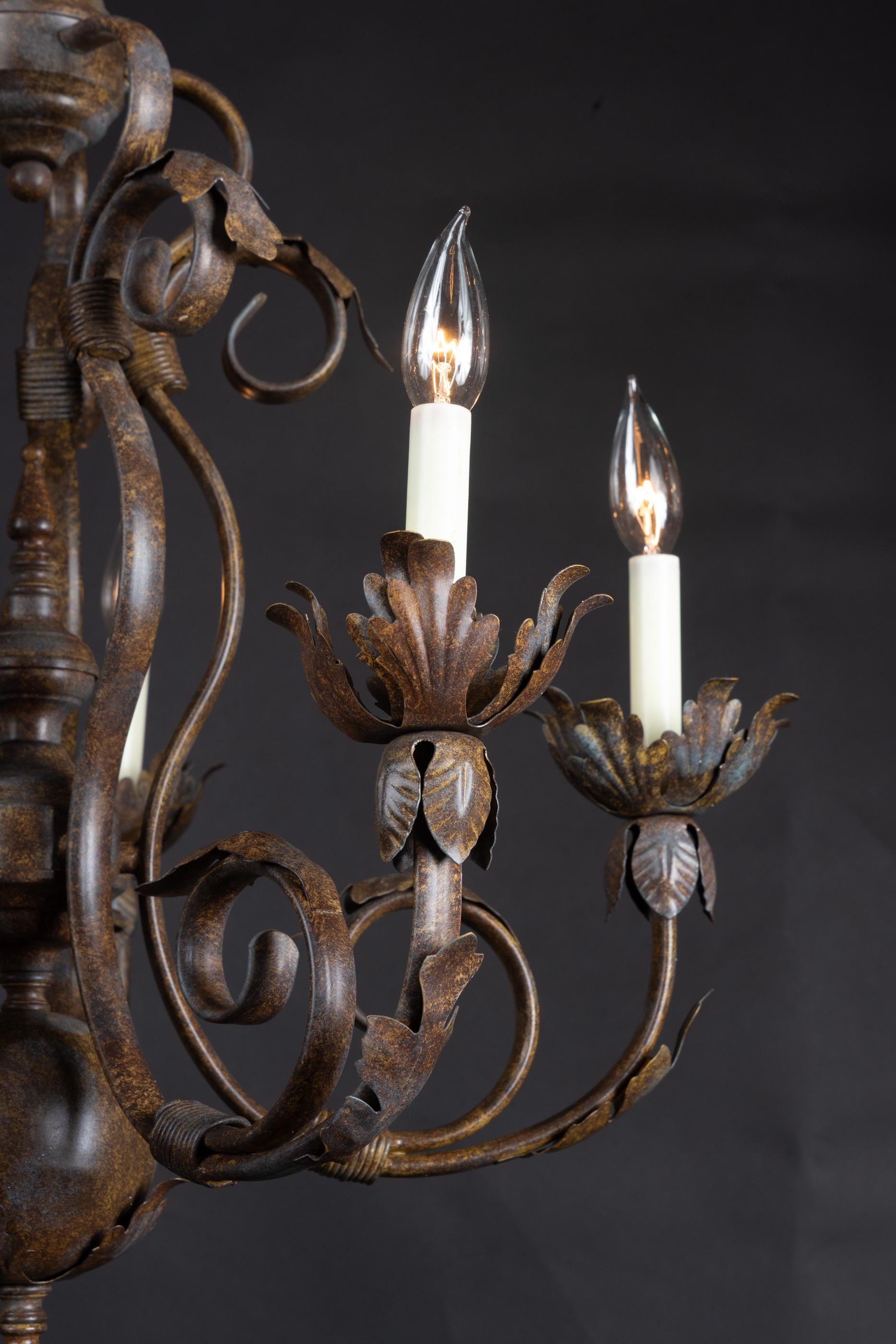 Beautiful mid 20th century Italian chandelier made of iron and tole. The piece features five lights and detailed floriate bobeches. Made in the Louis XV style, the piece features a decorative crown, swirling arms filled with movement, and a stately