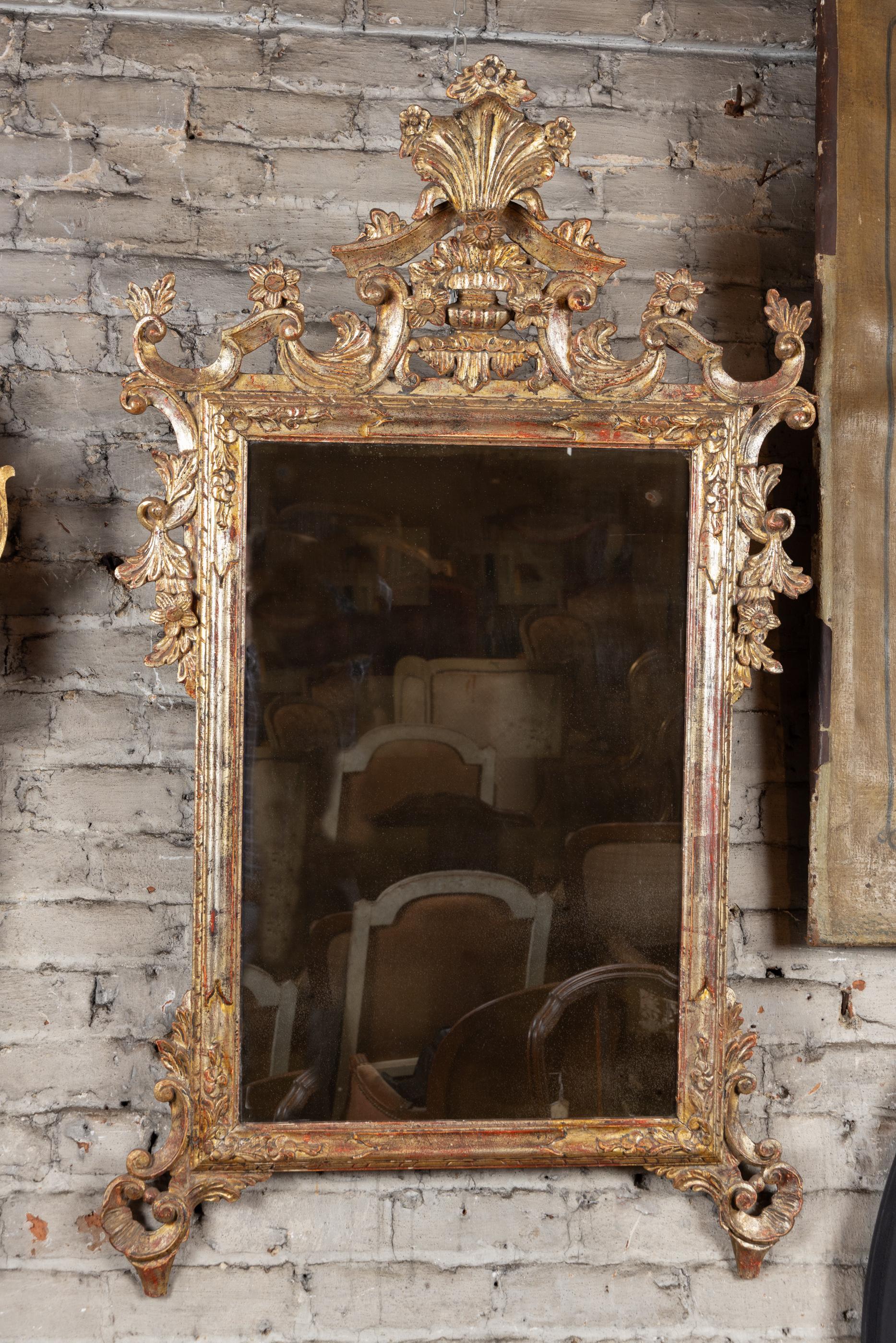 Bellissimo specchio italiano intagliato in stile rococò dei primi del Novecento. Il pezzo è caratterizzato da foglie d'argento e d'oro che producono un riflesso unico. Gli elementi scolpiti in alto, in basso e ai lati sono dettagliati e ben