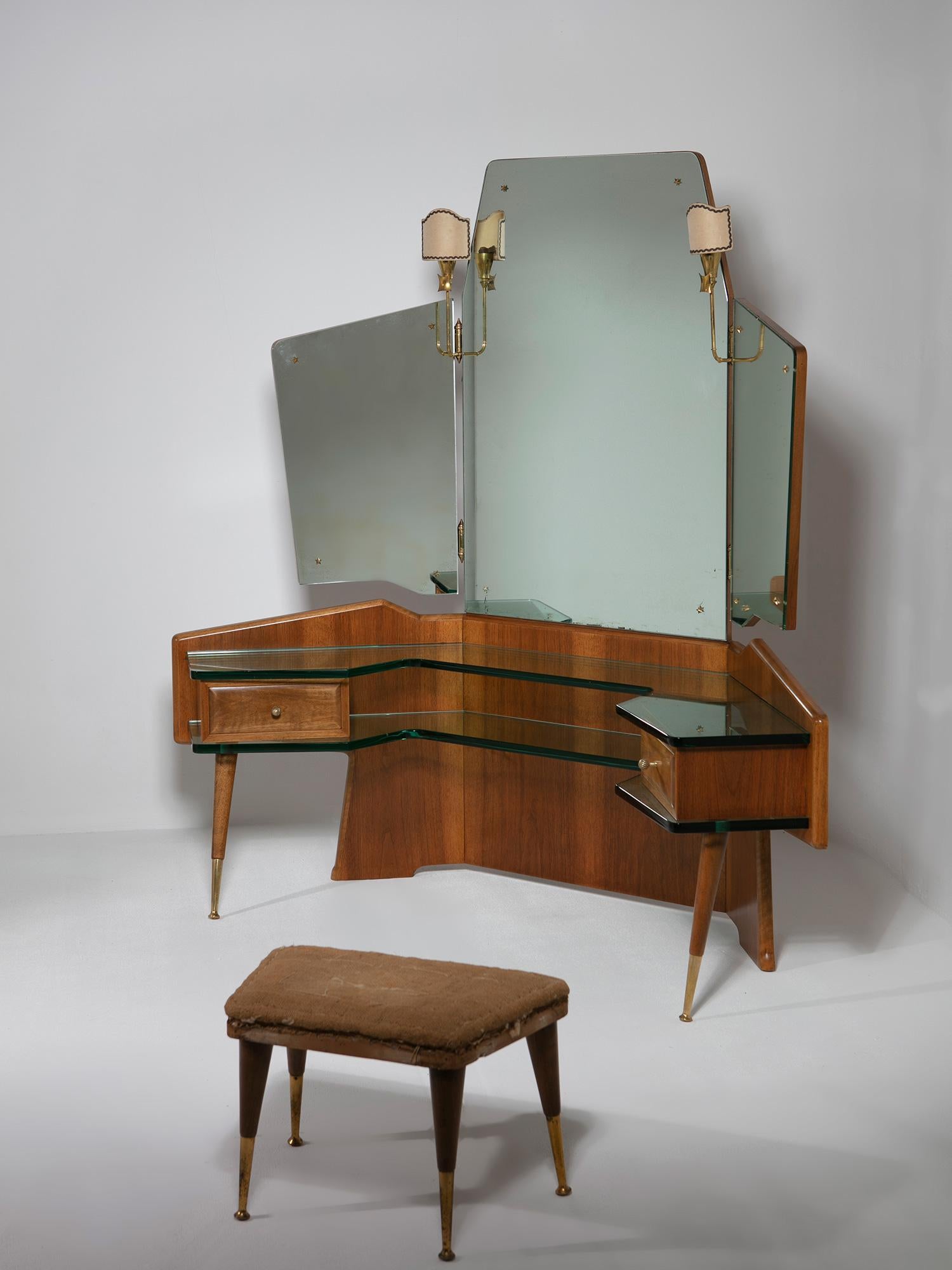 Italian 50s corner vanity attributed to Pietro Chiesa.
Central large mirror and two adjustable side mirrors with brass lamps.
Large green Nile glass tops incorporate drawers, legs and back frame.
Matching stool with brass details.