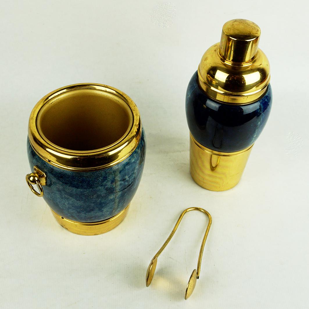 This original stunning cocktail or bar set in brass and blue coloured Goatskin covered wood was designed by Aldo Tura for Macabo and produced in Italy in the 1960s. The set includes a cocktail shaker and an ice bucket with tongue. 
The Ice Bucket