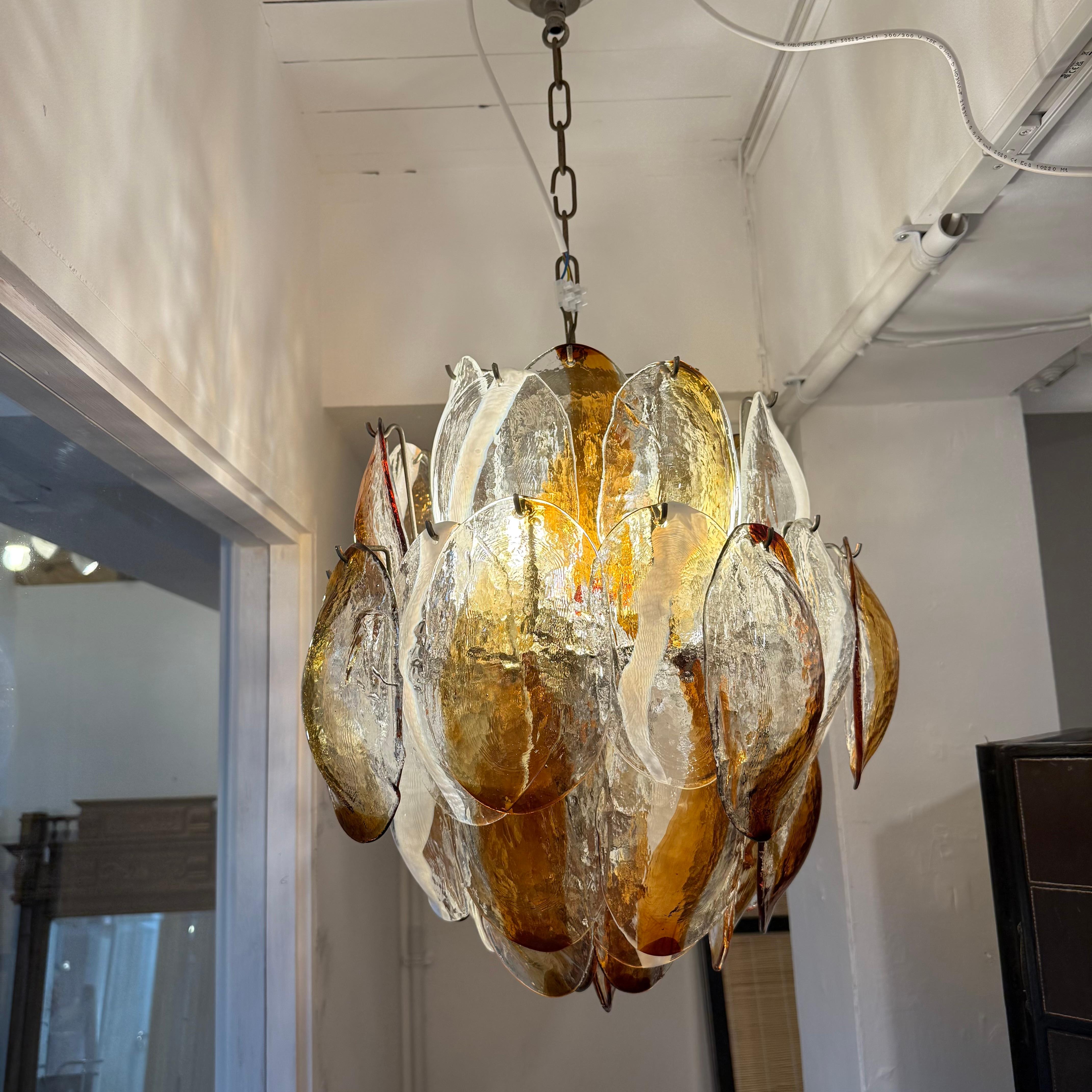 Lampadario italiano con strati di vetri di Murano ambra e trasparenti a forma di conchiglia montati su una struttura in ottone di Mazzega Murano. Due in magazzino. La catena può essere regolata o ridotta su richiesta.