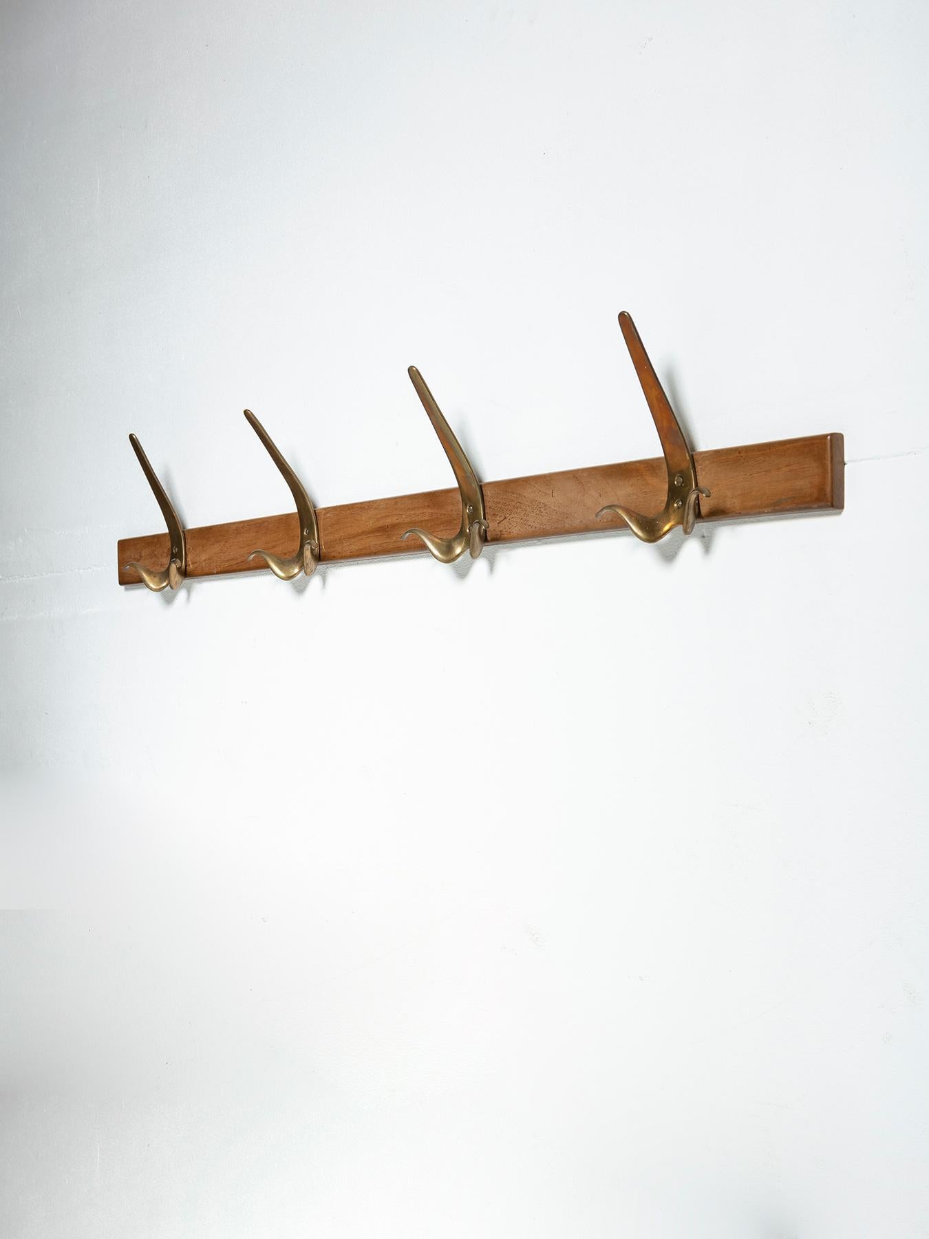 Rare coat rack composed by 4 bronze mustache shaped hooks on a wood bar.