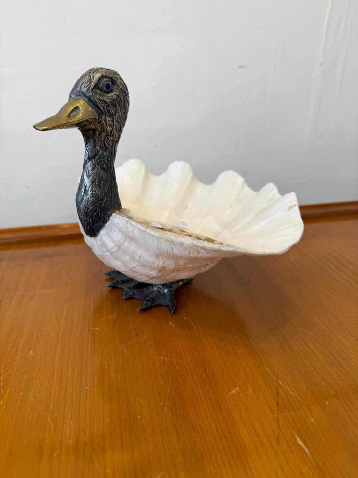 Precioso pato de concha de almeja diseñado y fabricado por Gabriella Binazzi, Italia, hacia la década de 1970.
Concha de almeja montada sobre pies plateados y decorada con cabeza de pato plateada.