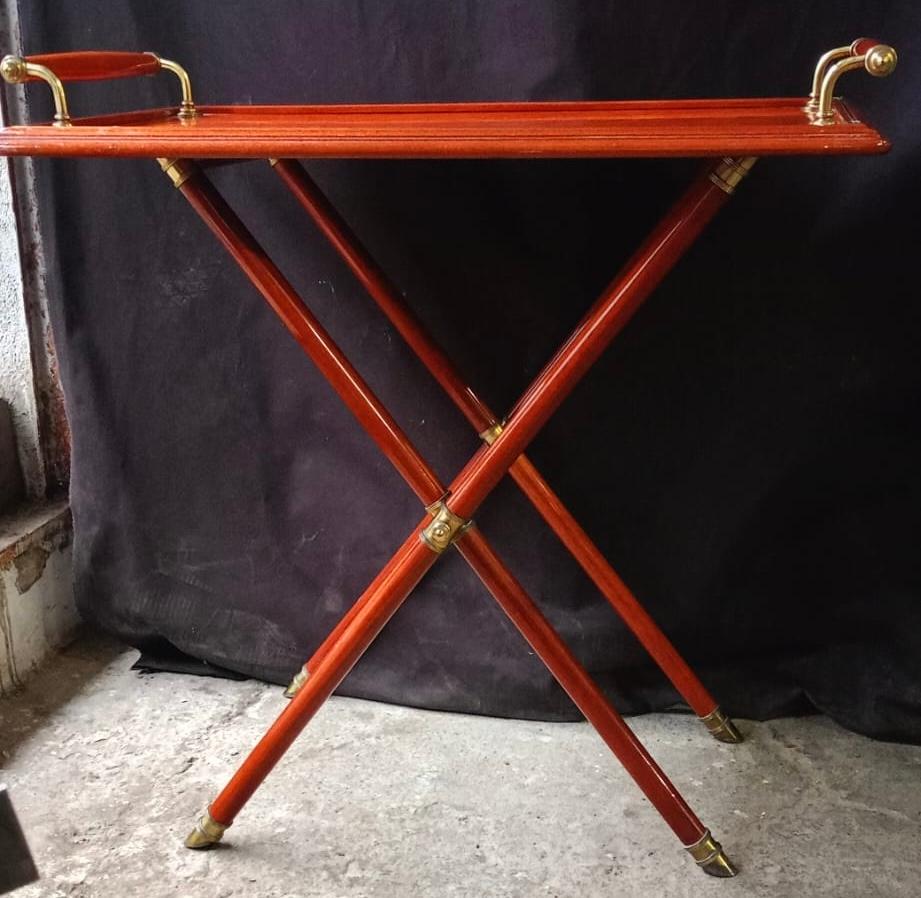 This nice 1970's Italian serving folding table in the style of the Pier Fornasetti  with removable tray in red lacquered wood with a brass handles and sabots and brass bar in the middle 