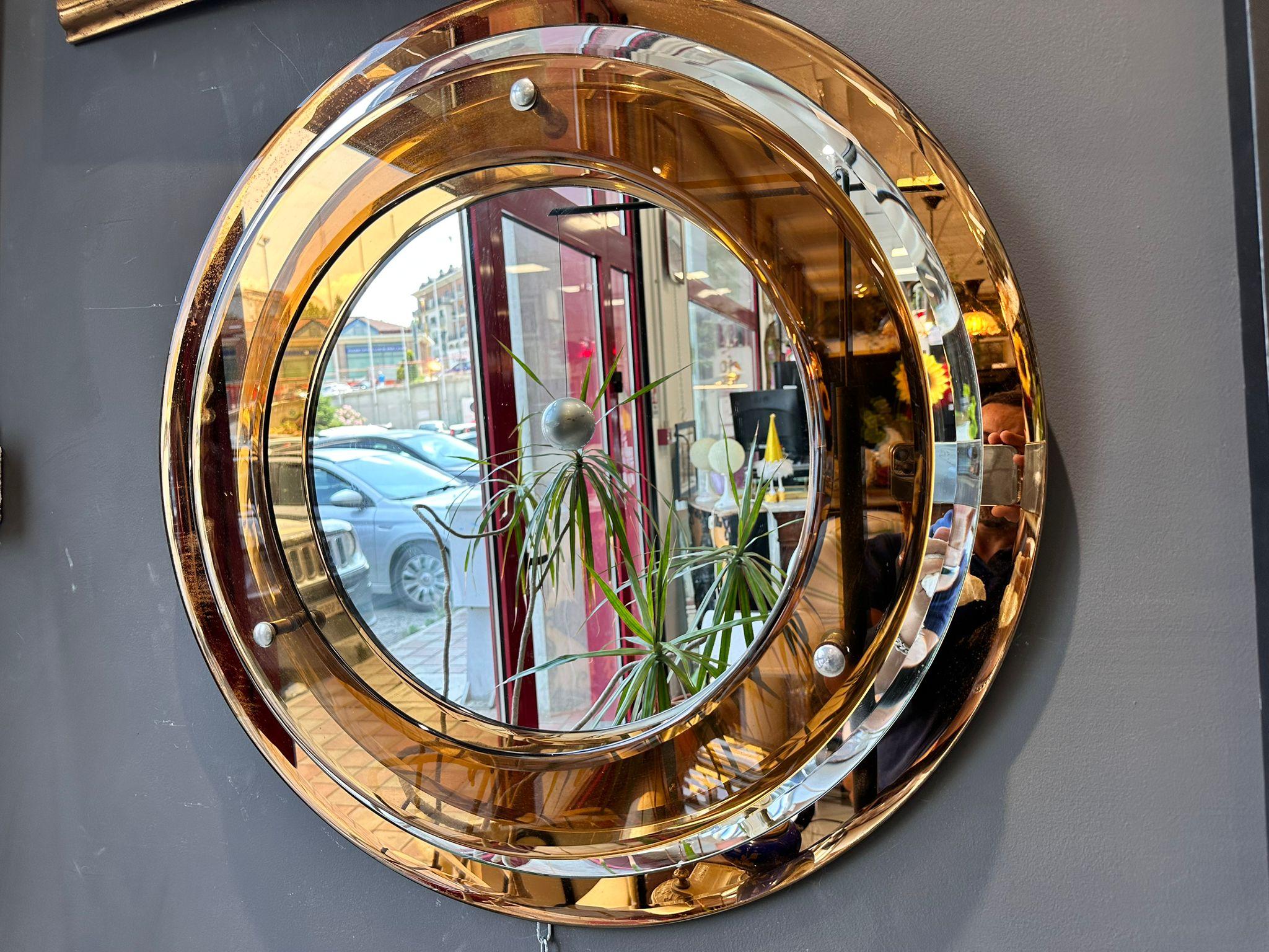 An stunning circular wall mirror, with three circular glass rings in clear and amber colour glass surrounding mirror. Italian c.1970's by Crystal Art   