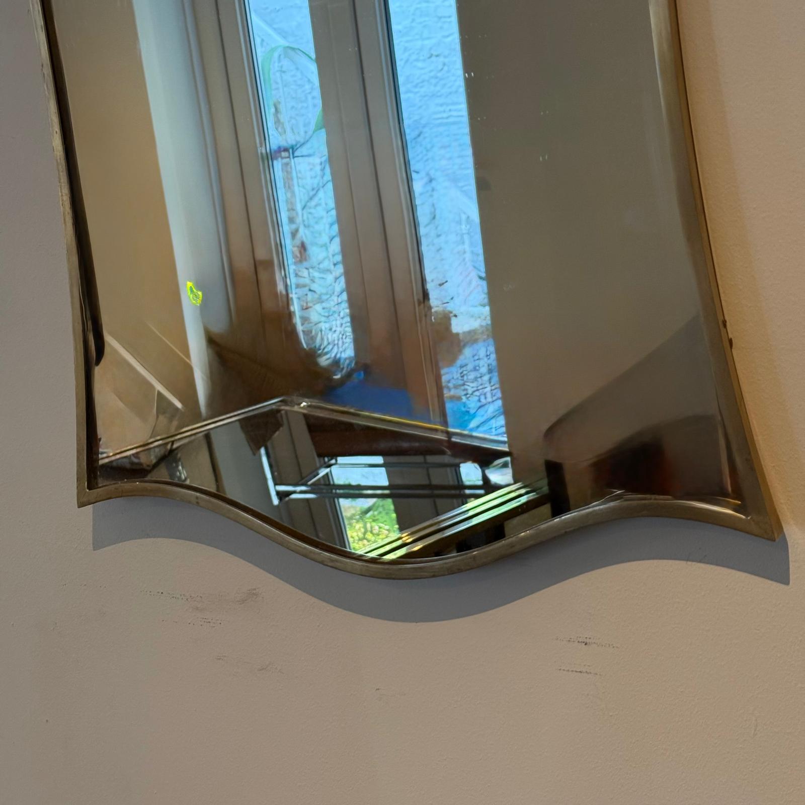 Italian 70's mirror in fine brass polished frame with wive design on the top and bottom, have marks on brass frame that can be polished with a Brasso 