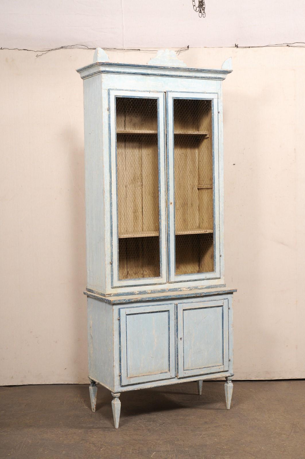A tall Italian painted-wood hutch cabinet, with wire-front doors. This vintage hutch from Italy, standing approximately 8.25 feet in height, has a two-piece buffet à deux-corps design (which references the two cabinet parts). The upper case, which