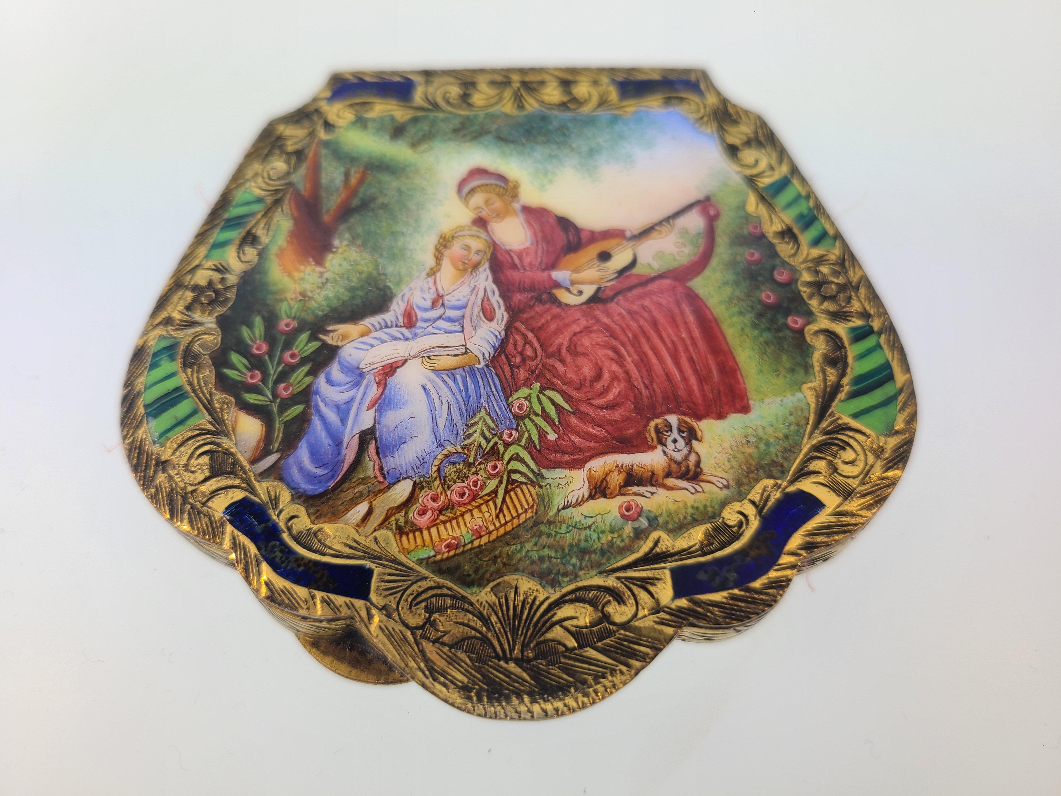 Italian 800 silver with gold vermeil and hand painted compact.

This compact features beautiful gold vermeil over 800 silver with an etched scroll design. Hand painted Italian garden scene on one side, with painted enamel detail. Beveled mirror with