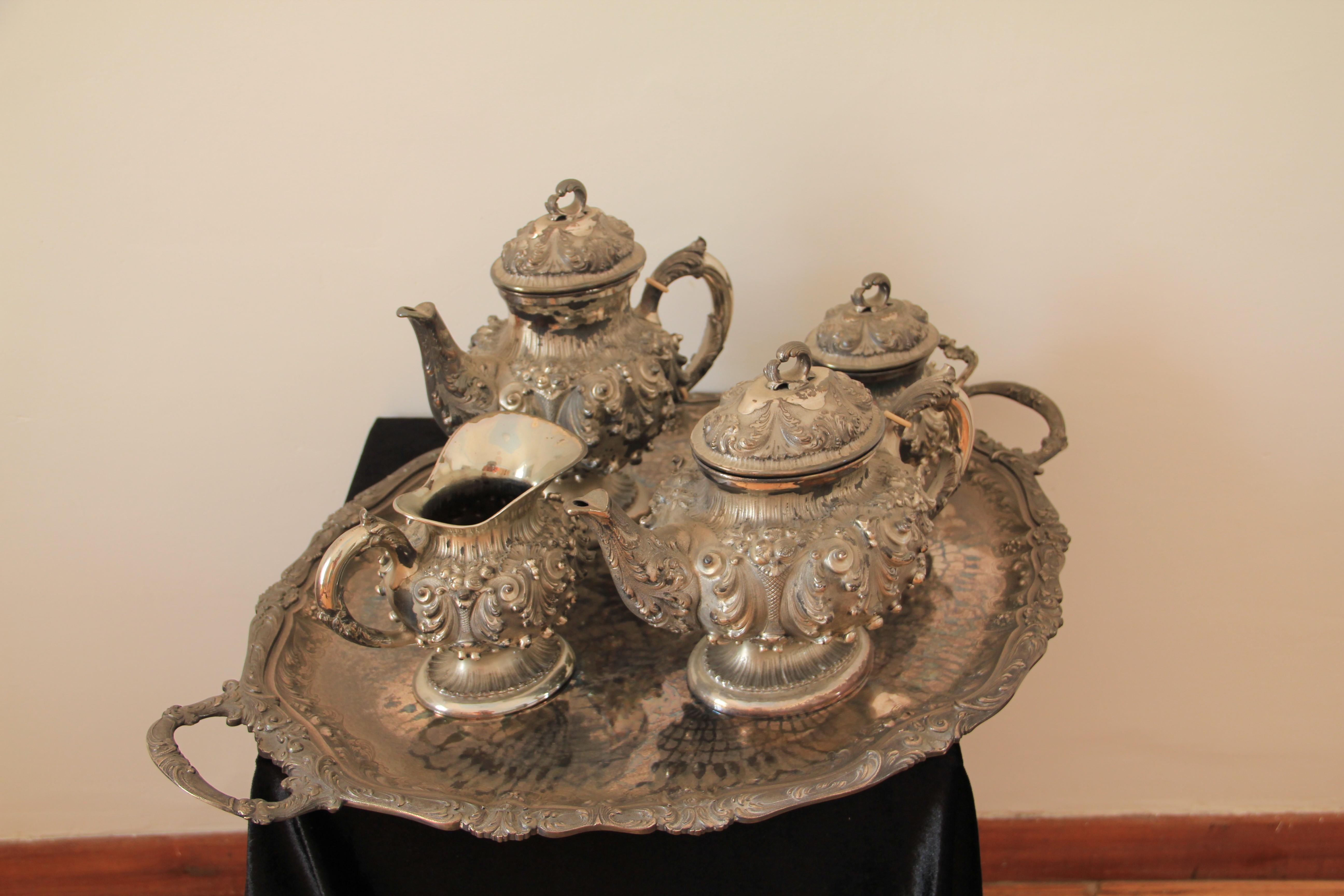 Each piece of baluster form richly embossed with vases of flowers, leaf scrolls and shell-work, on a conforming circular pedestal foot, leaf capped scroll handles, the lids with leaf scroll finials, comprising a tea pot, coffee pot, milk jug and