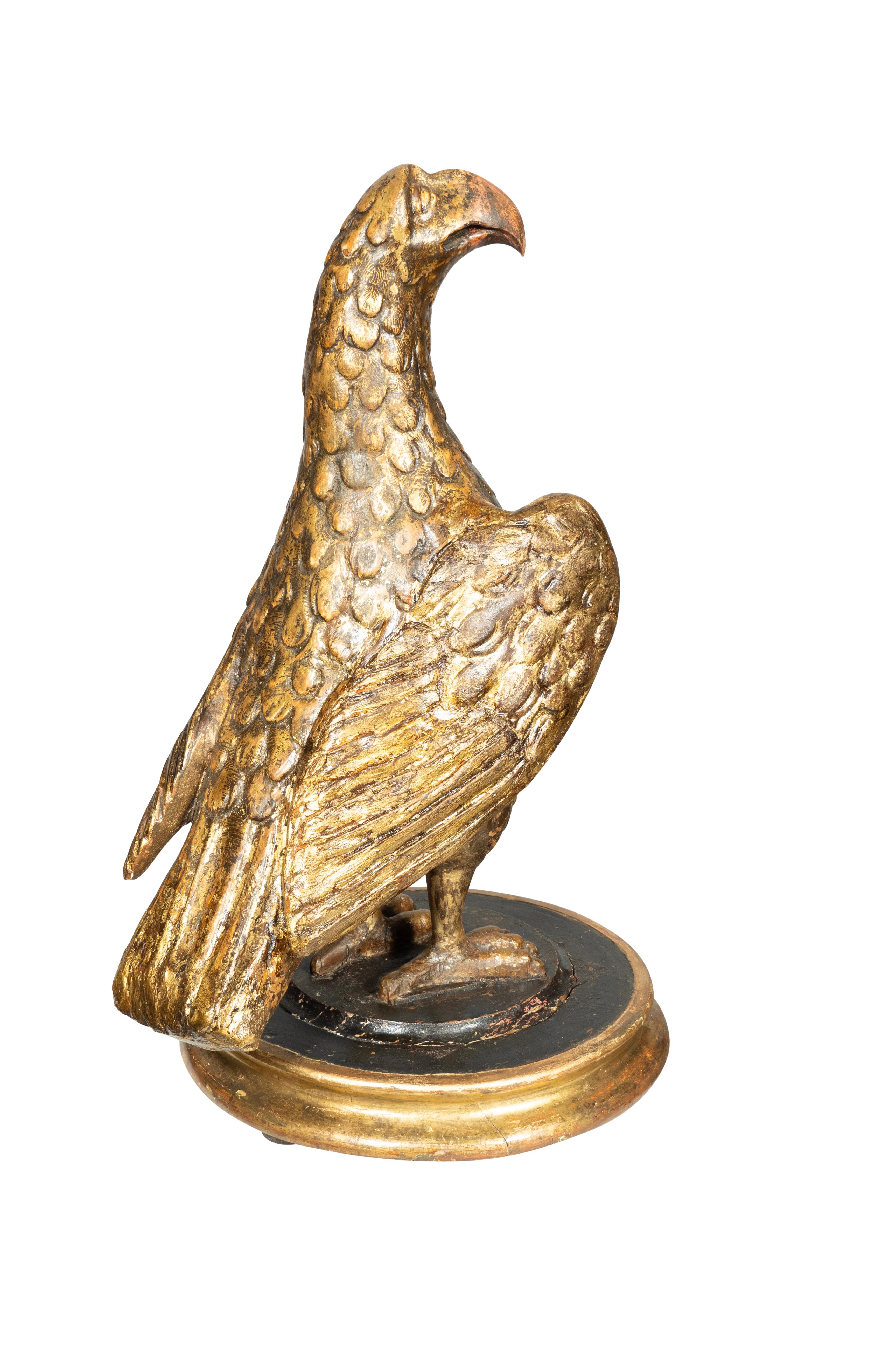 El águila en pie con la cabeza girada sobre una base circular. 