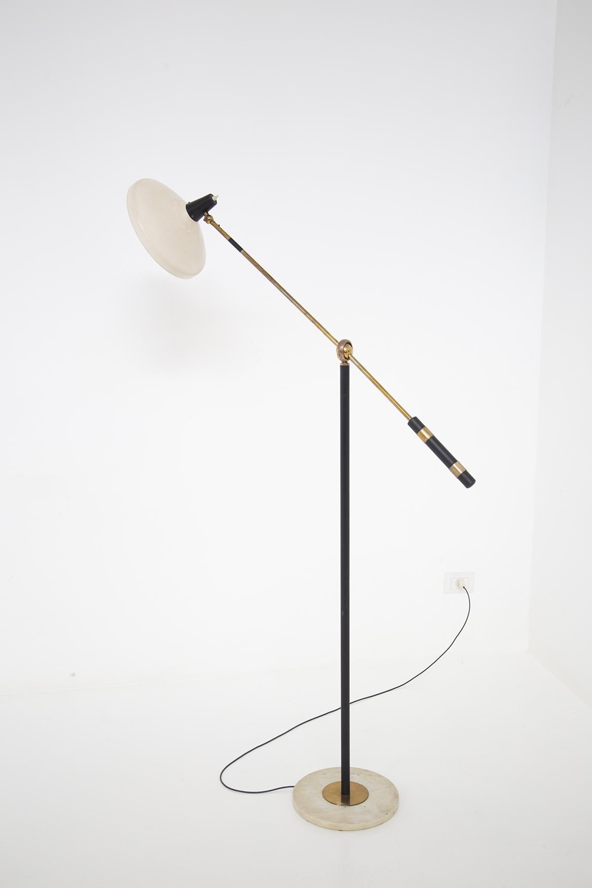 Beautiful adjustable brass and marble floor lamp designed in the 1950s of fine Italian manufacture.
The floor lamp has a supporting base, which makes the floor lamp stable, made of clear marble with a round brass center.
The stem, on the other